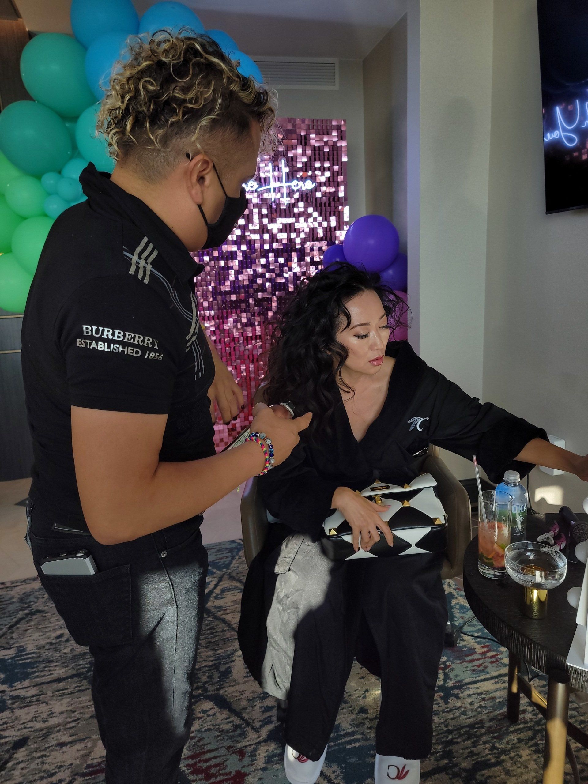 A woman is getting her hair done by a man wearing a mask