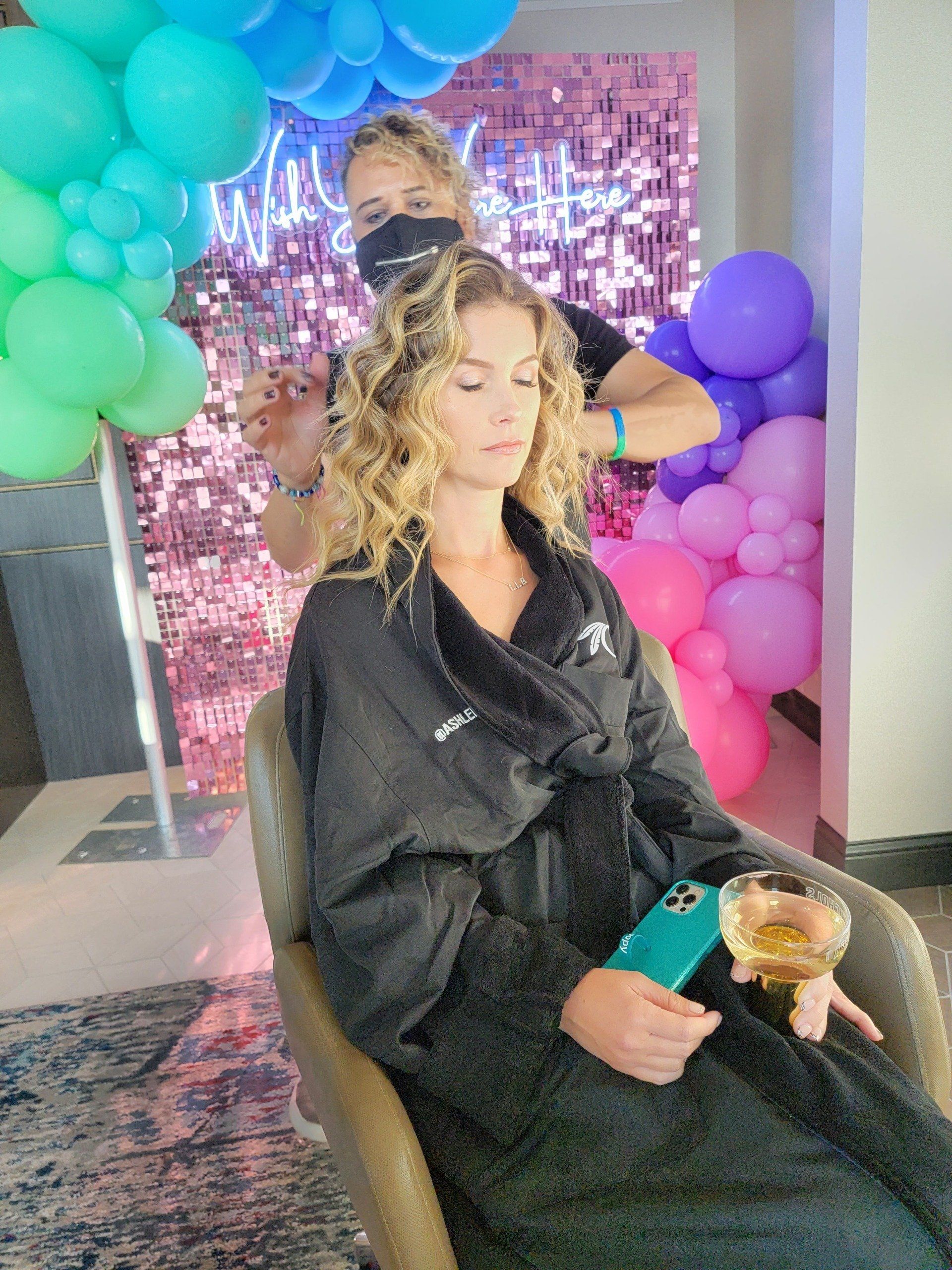 A woman is sitting in a chair getting her hair done by a hairdresser.