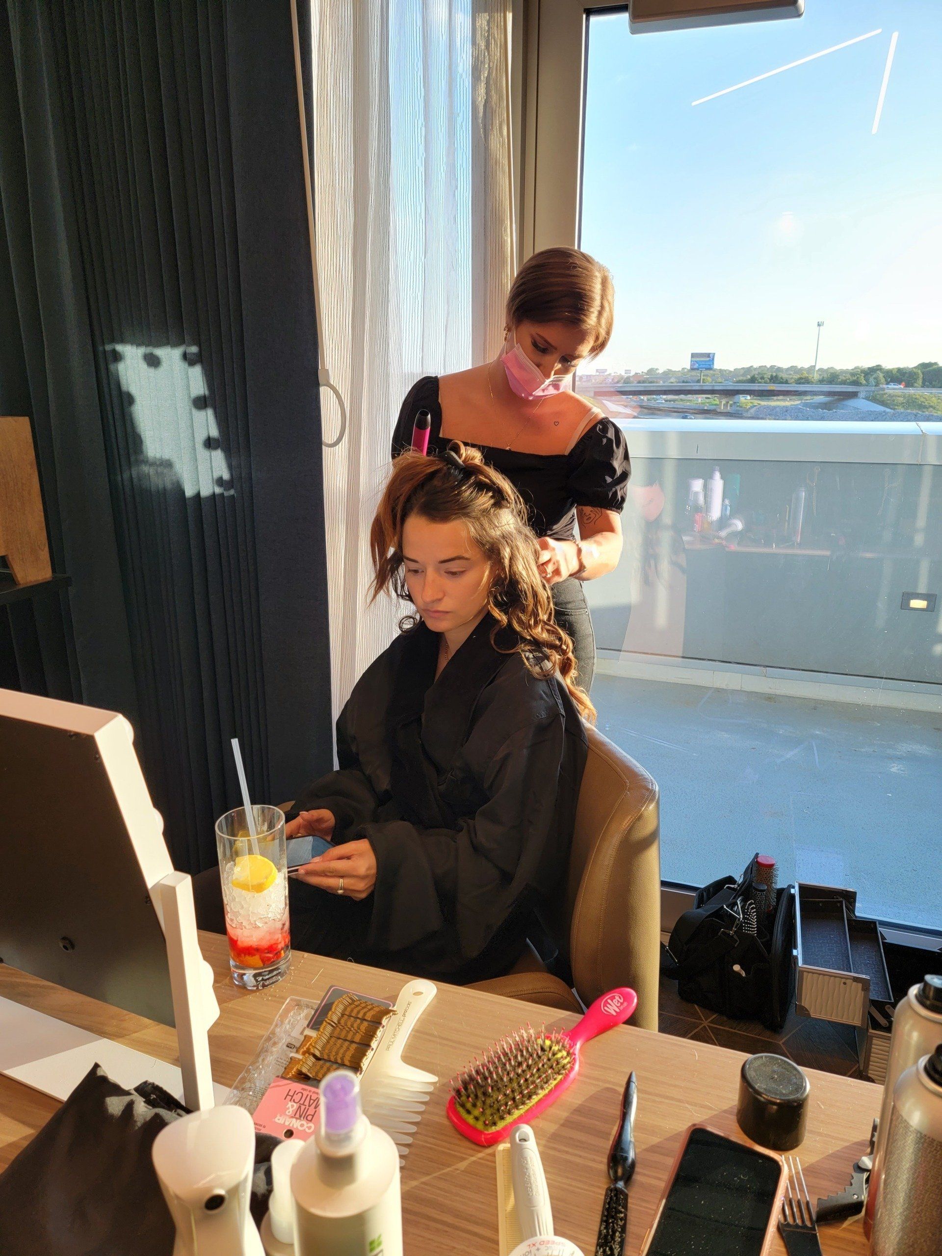A woman is brushing another woman 's hair in a room.