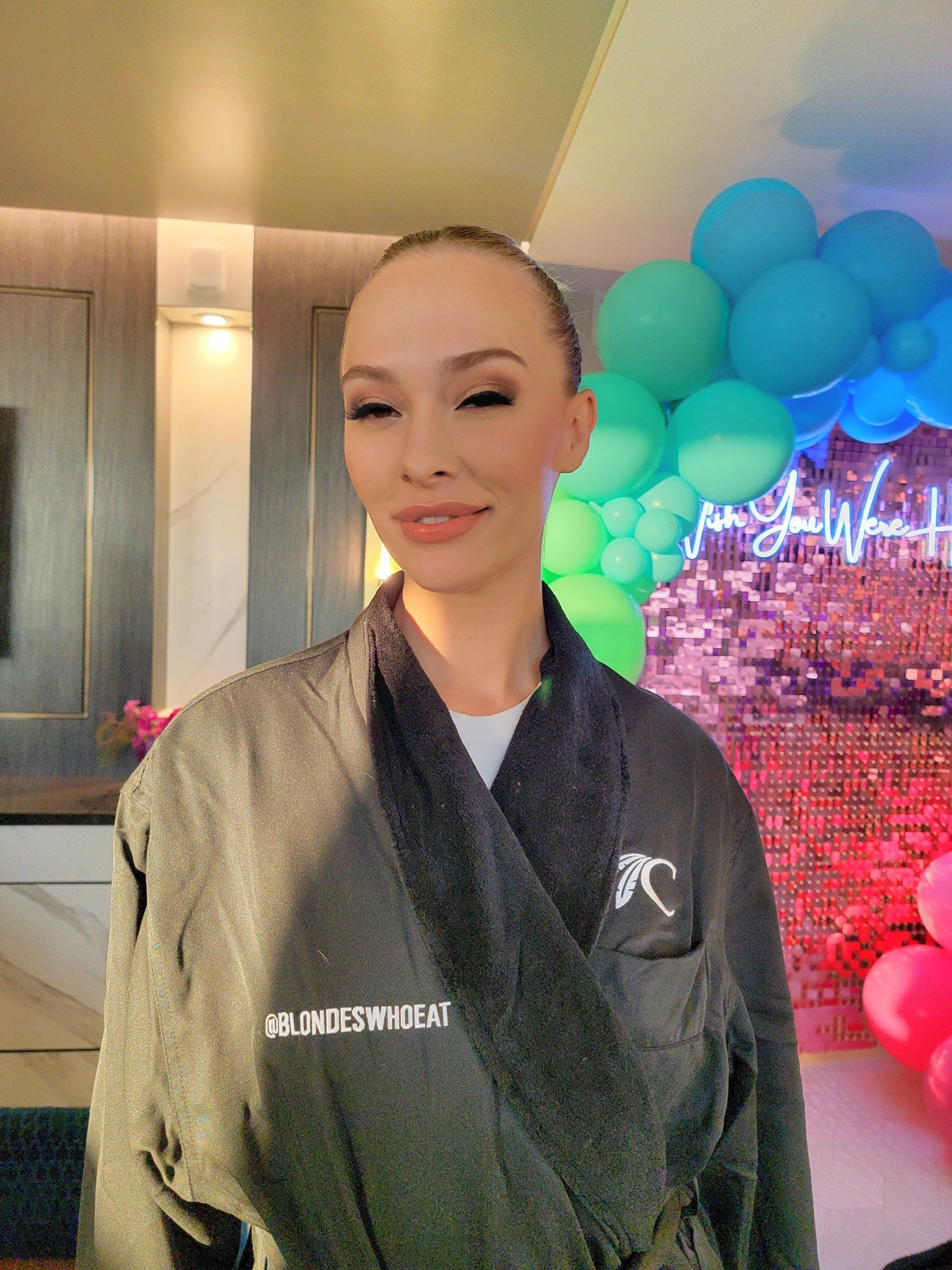 A woman in a robe is standing in front of balloons.