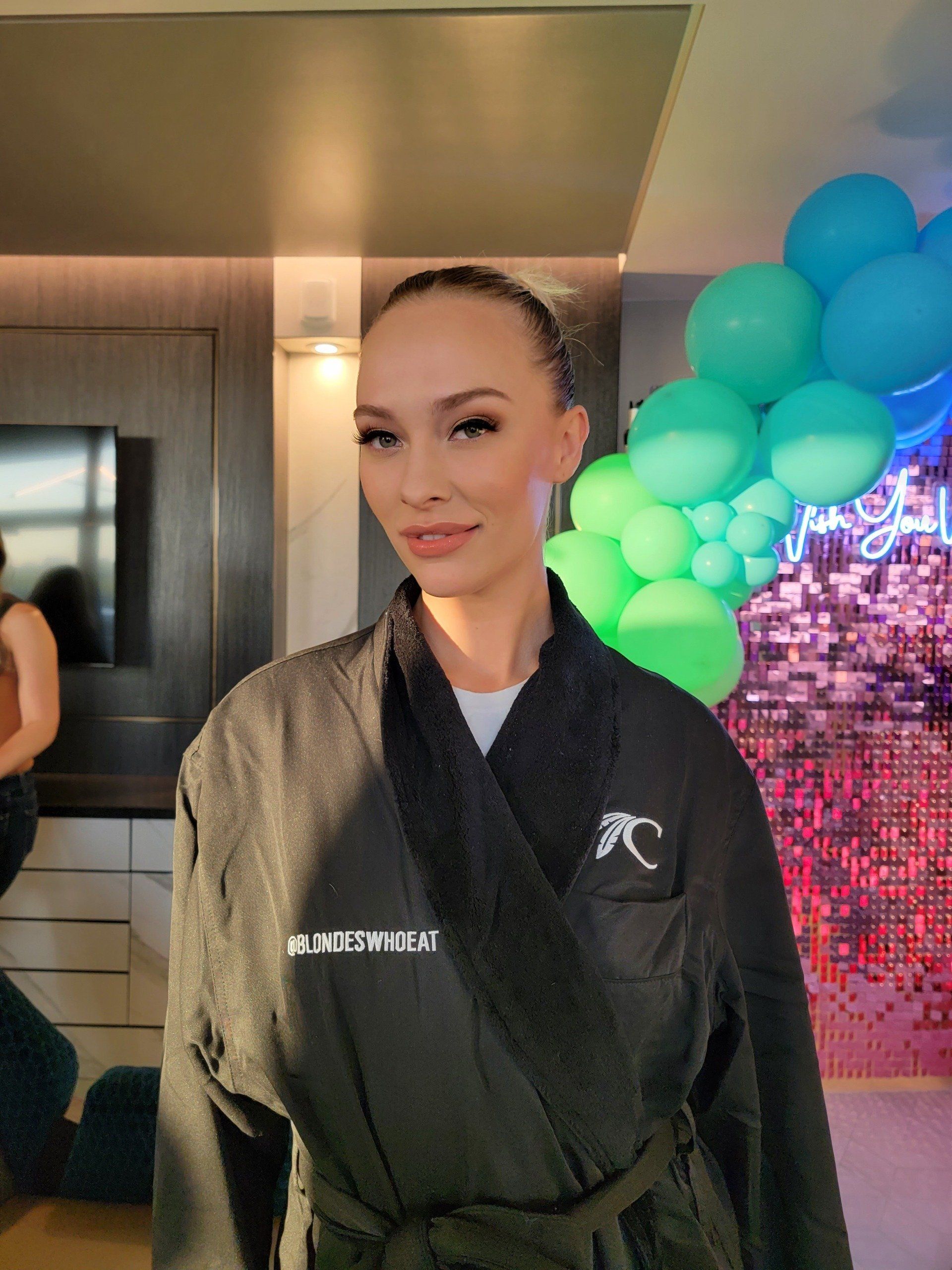 A woman in a robe is standing in front of balloons.