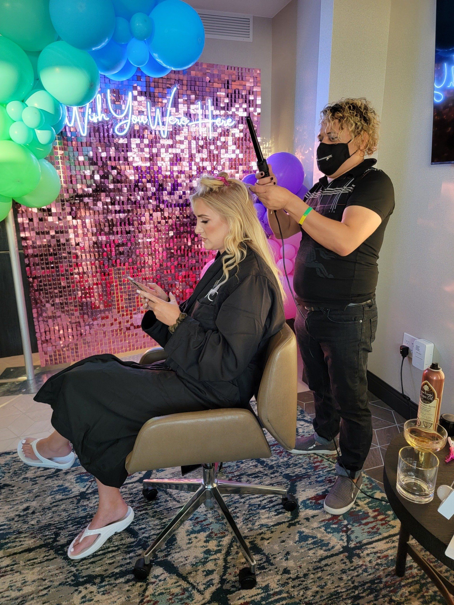 A woman is sitting in a chair getting her hair done by a hairdresser.