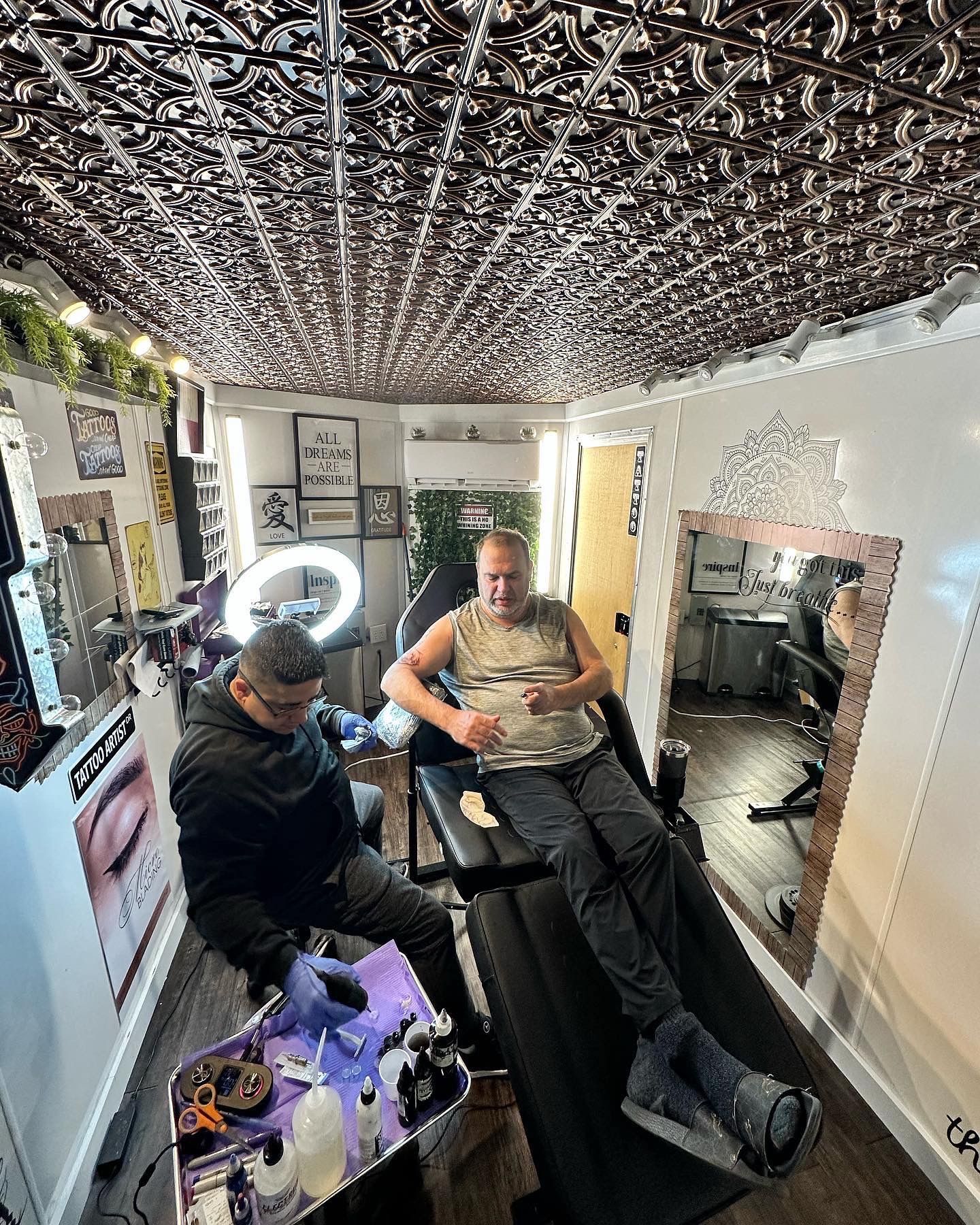 A man is getting a tattoo in a tattoo studio.