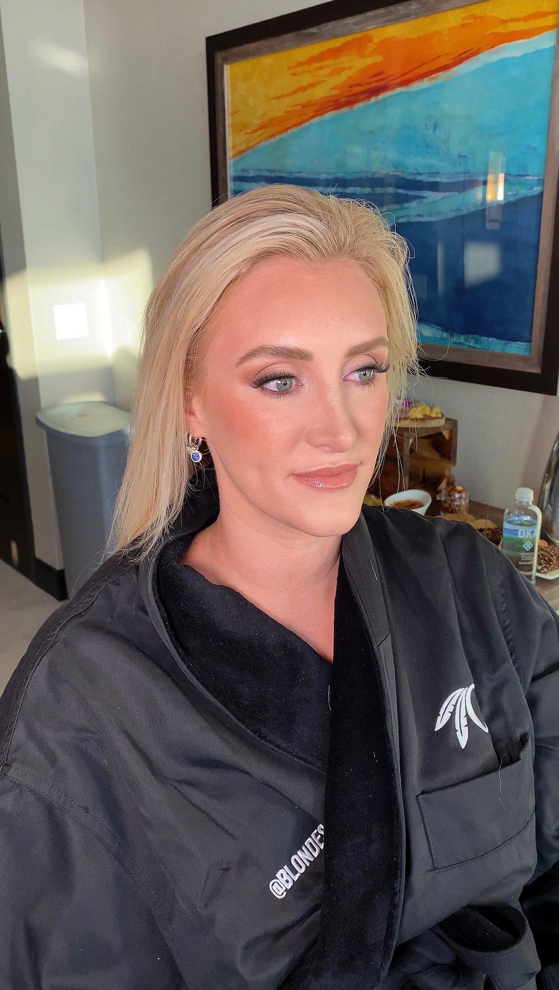 A woman in a black robe is sitting in a chair in front of a painting.