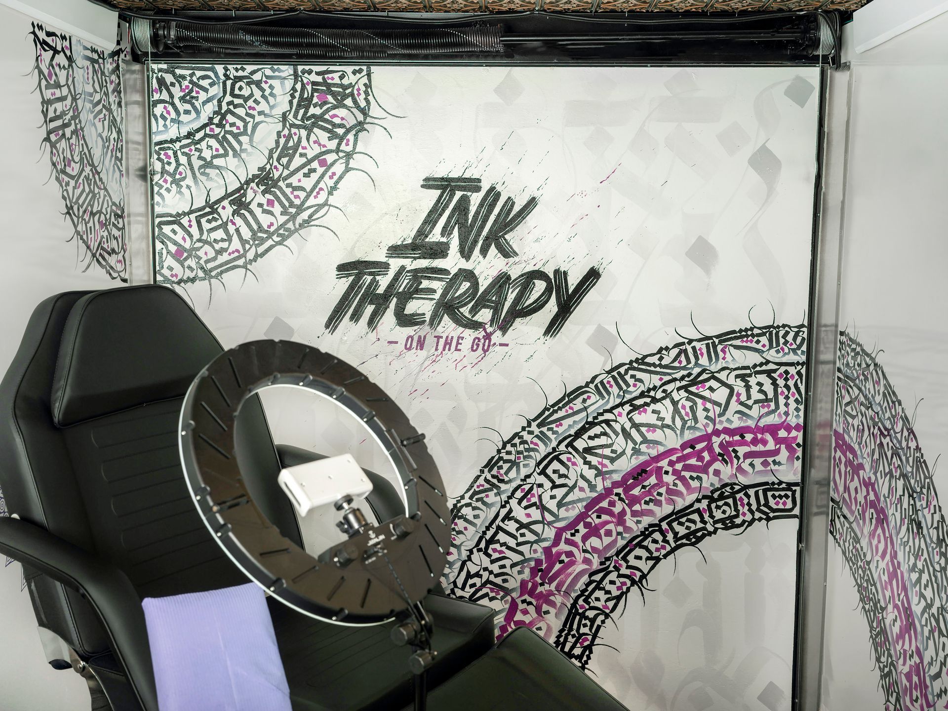 A chair with a ring light on it in a tattoo studio.