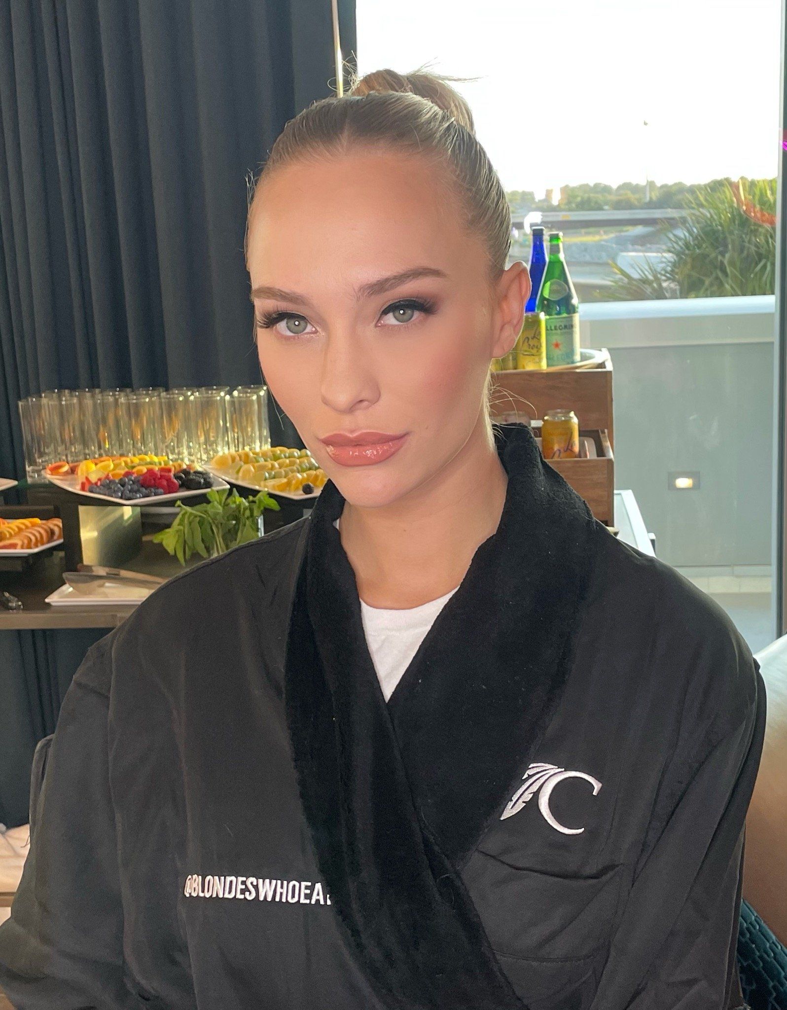 A woman in a black robe is sitting in front of a window.
