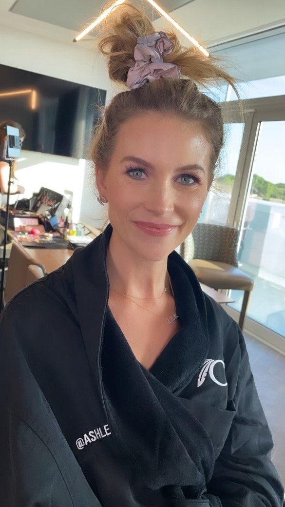 A woman is wearing a black robe and a purple scrunchie in her hair.