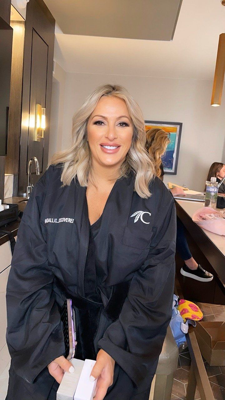 A woman in a black robe is sitting on a stool in a room.