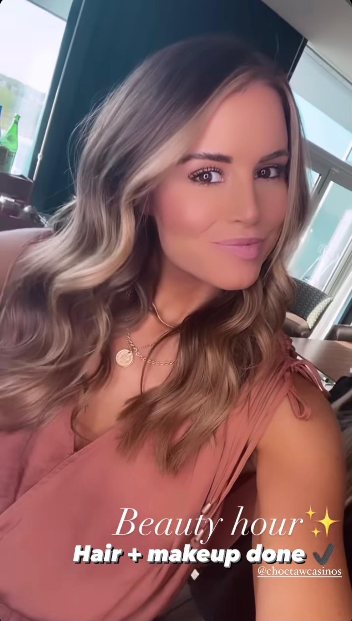 A woman is taking a selfie with her hair and makeup done.