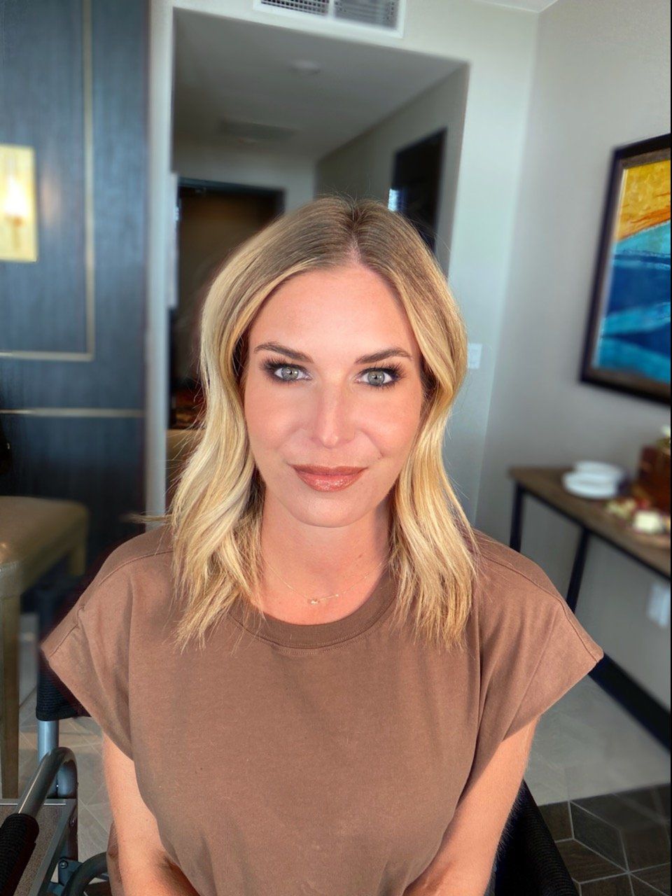 A woman in a brown shirt is smiling in a room