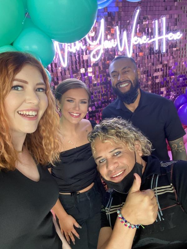 A group of people are posing for a picture with balloons in the background.