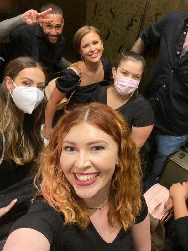 A group of people wearing face masks are taking a selfie in an elevator.