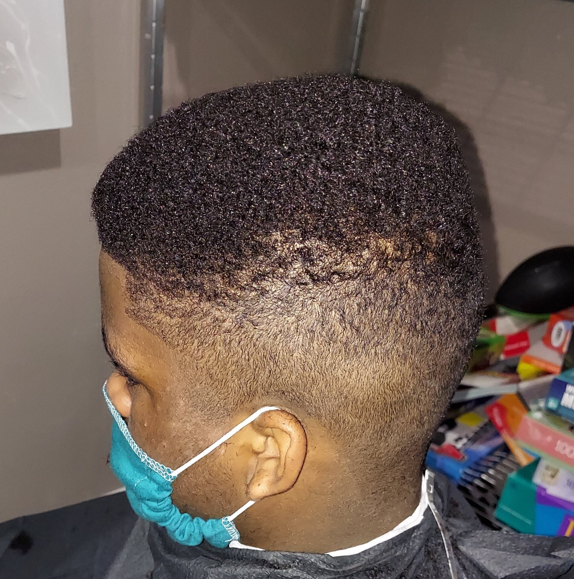 A man wearing a face mask is getting his hair cut.