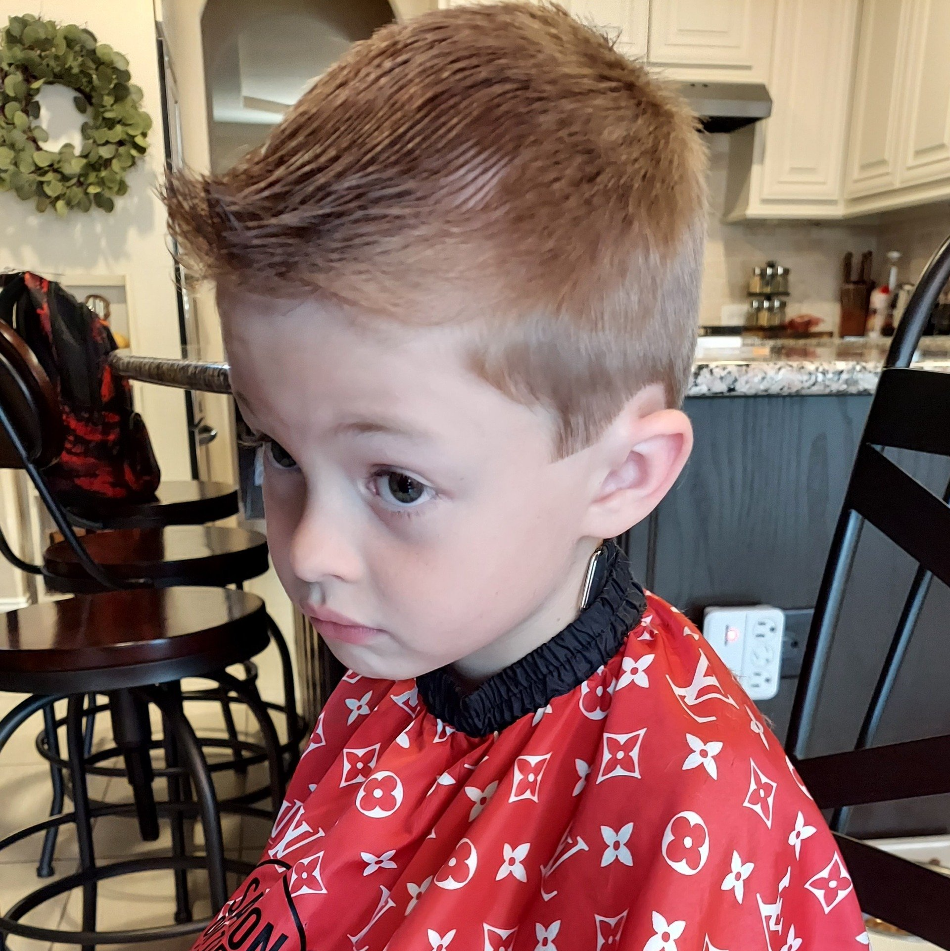 A young boy wearing a red louis vuitton cape