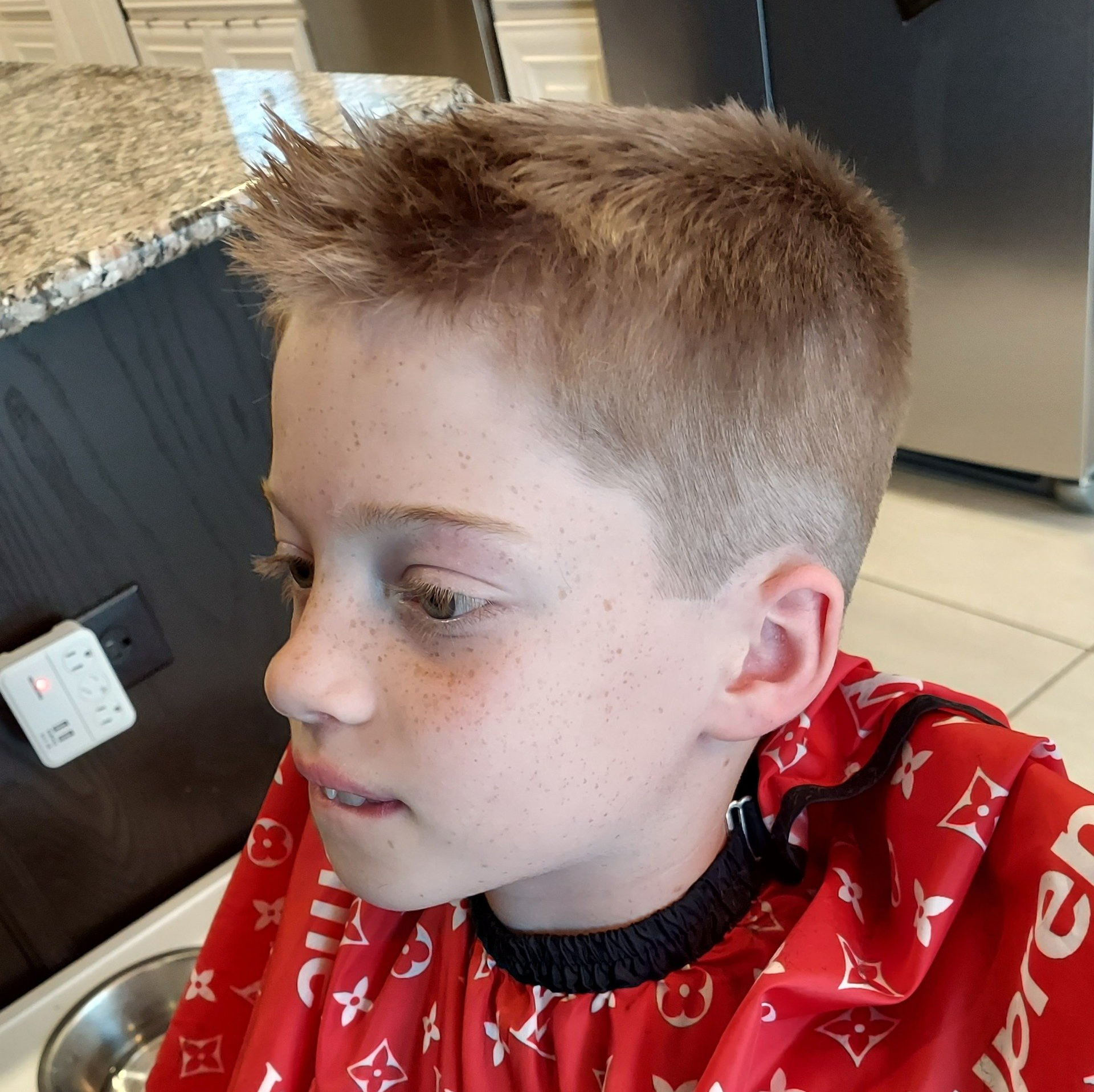 A young boy is wearing a red louis vuitton apron