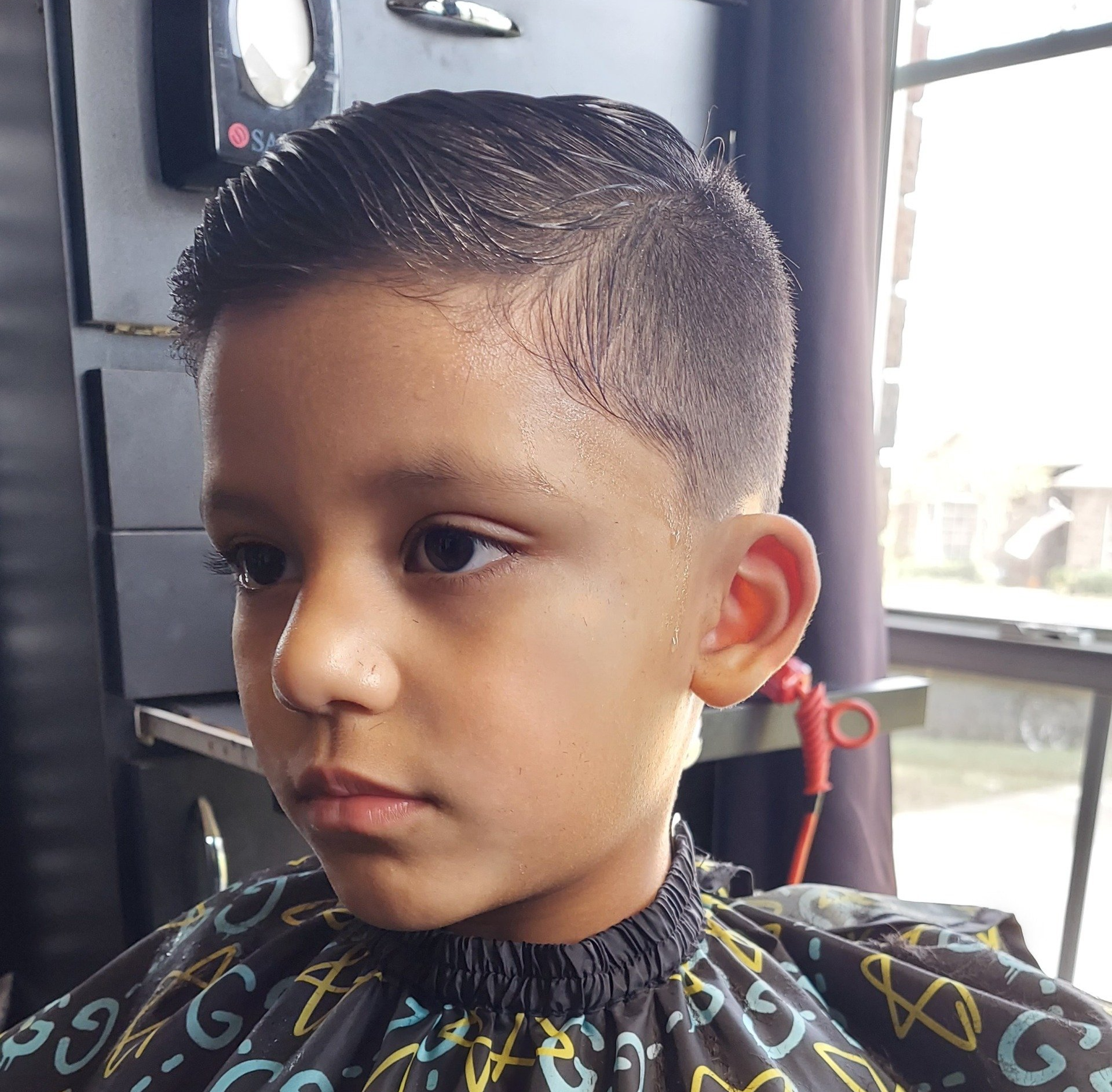 A young boy is getting his hair cut at a barber shop