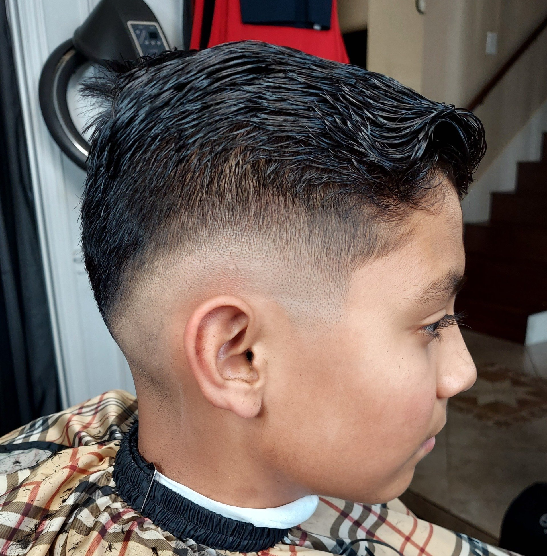 A young boy is getting his hair cut at a barber shop
