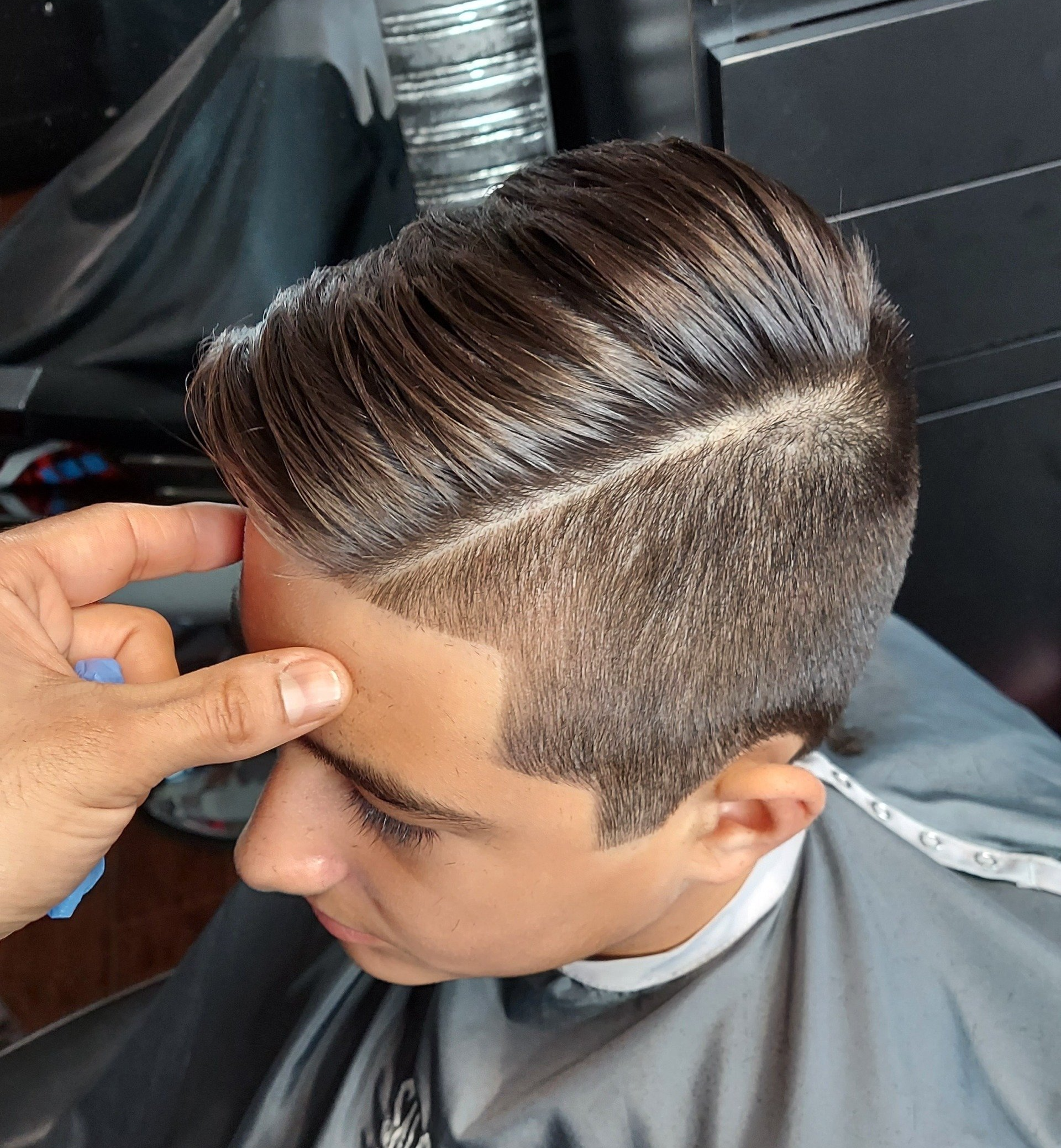 A man is getting his hair cut at a barber shop.