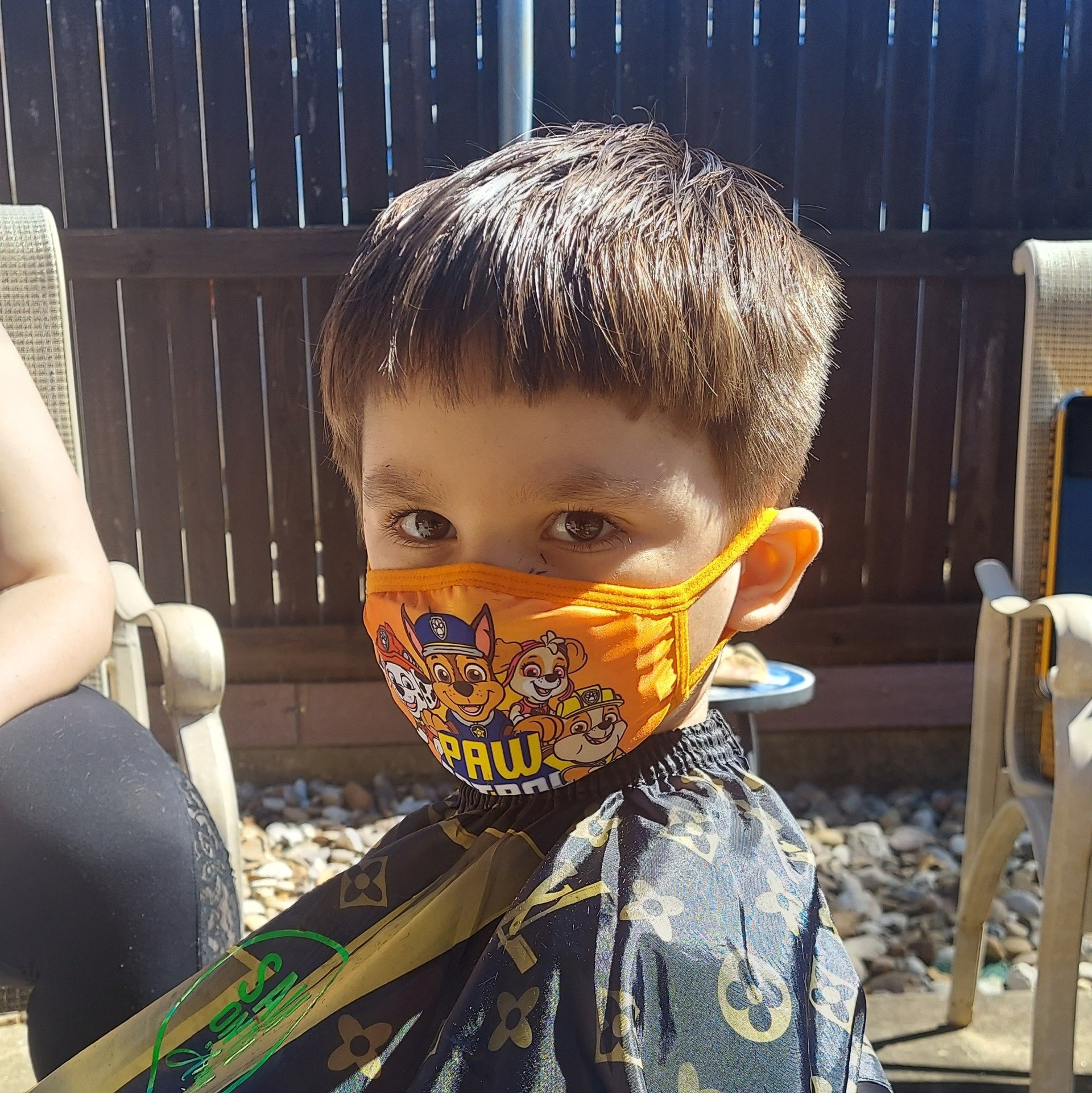 A young boy wearing an orange paw patrol face mask