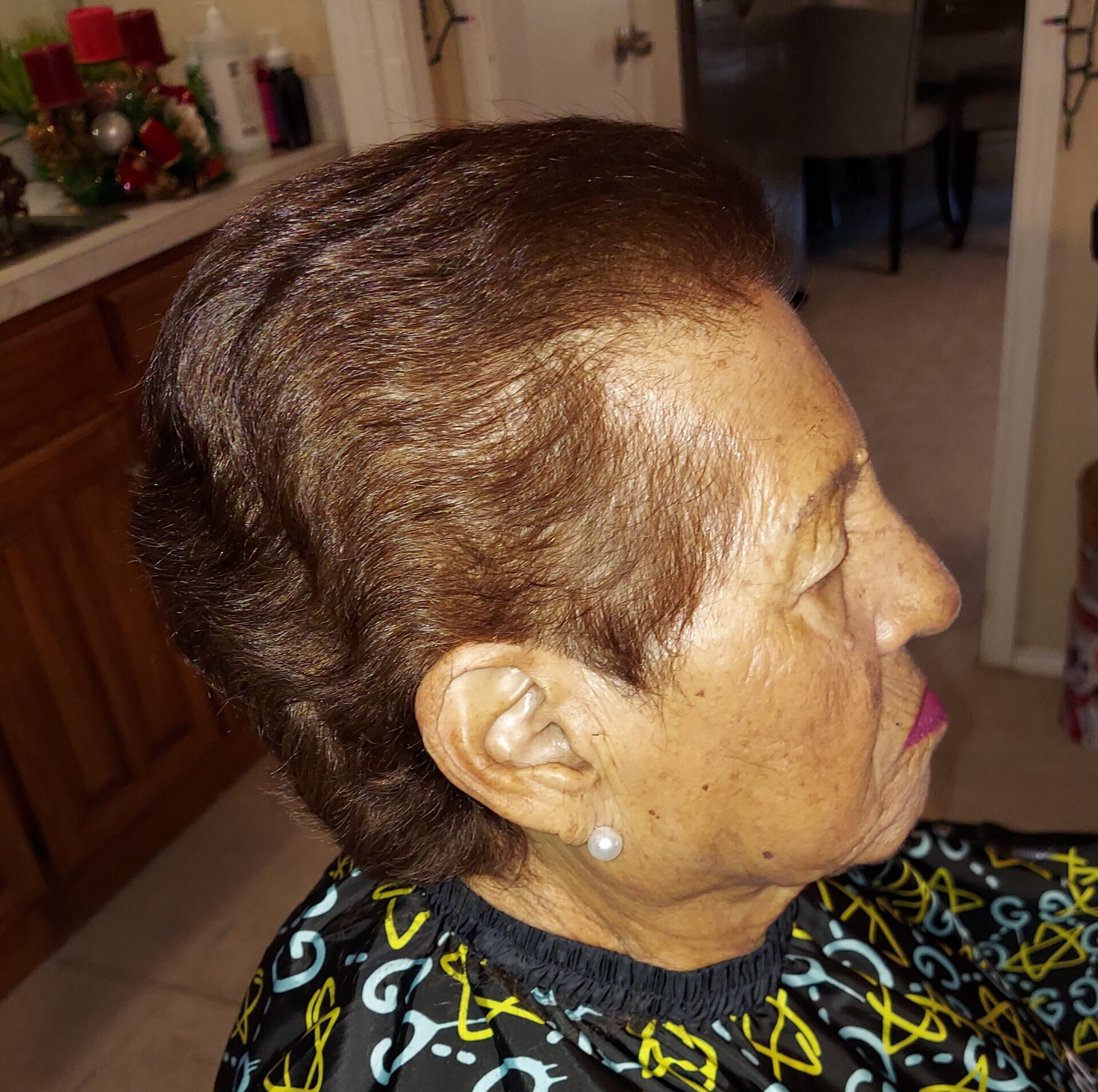 A woman wearing a black and yellow apron has her hair cut