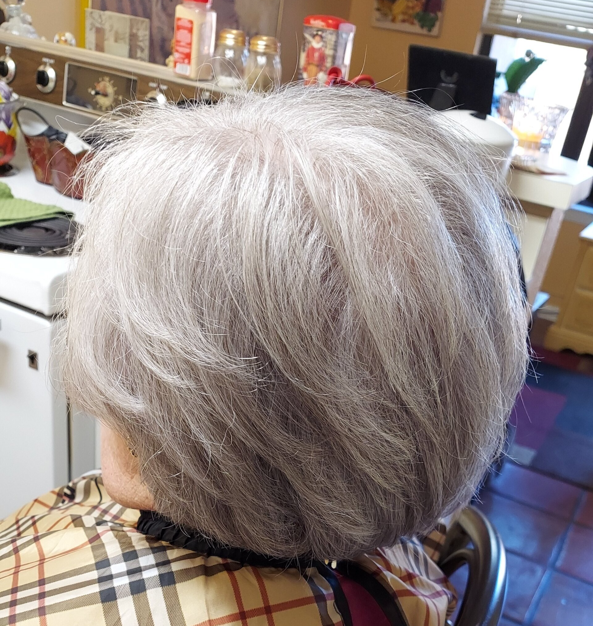 A woman with gray hair is wearing a plaid shirt