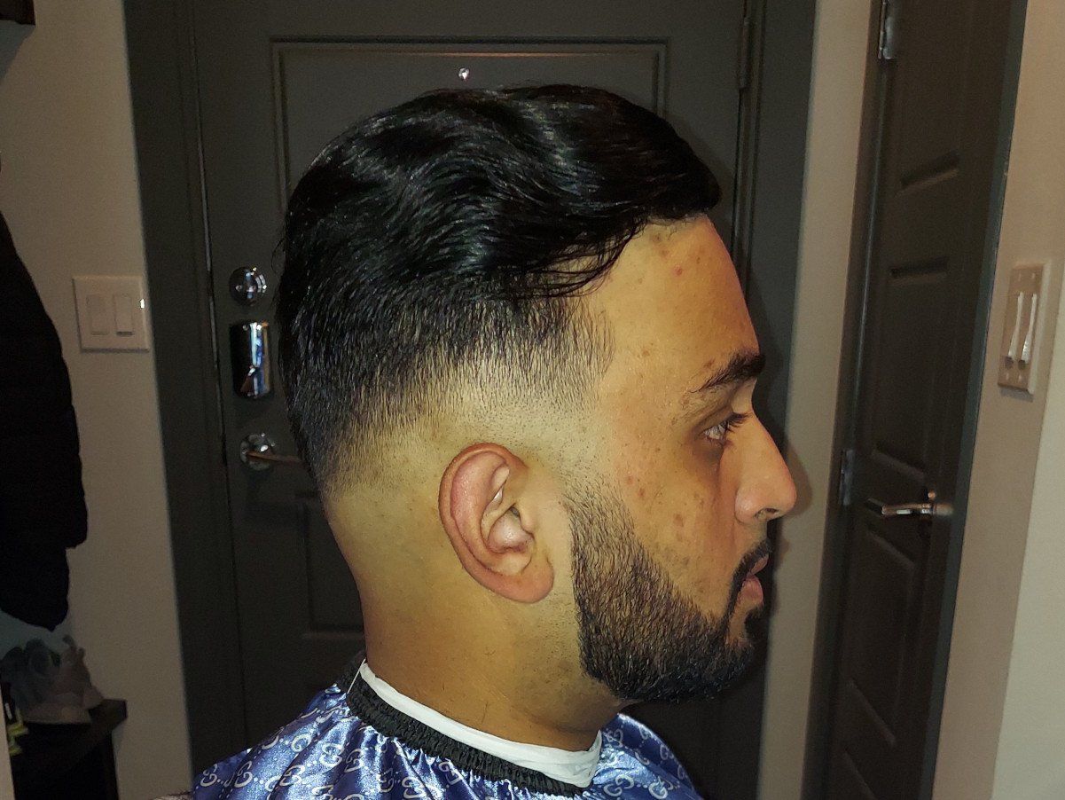 A man with a beard is getting his hair cut by a barber.