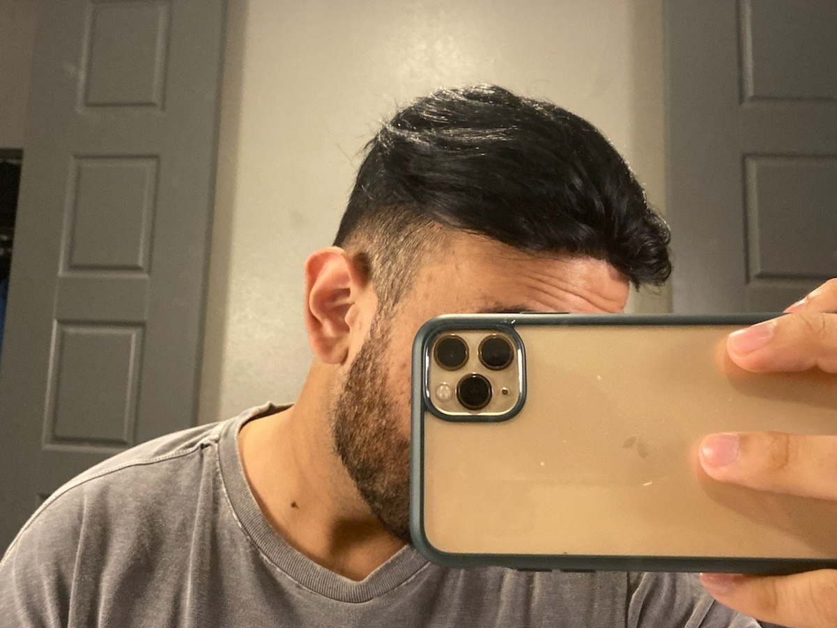 A man is taking a selfie with his phone in front of a mirror.