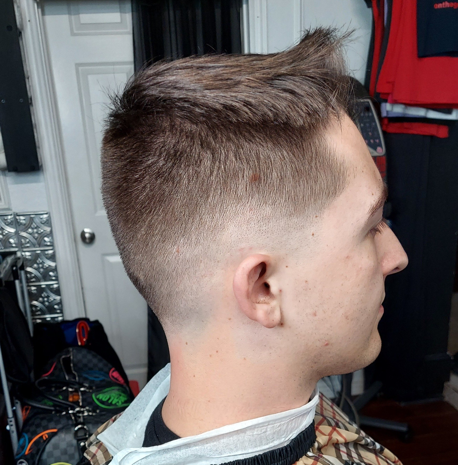 A man is getting his hair cut at a barber shop.