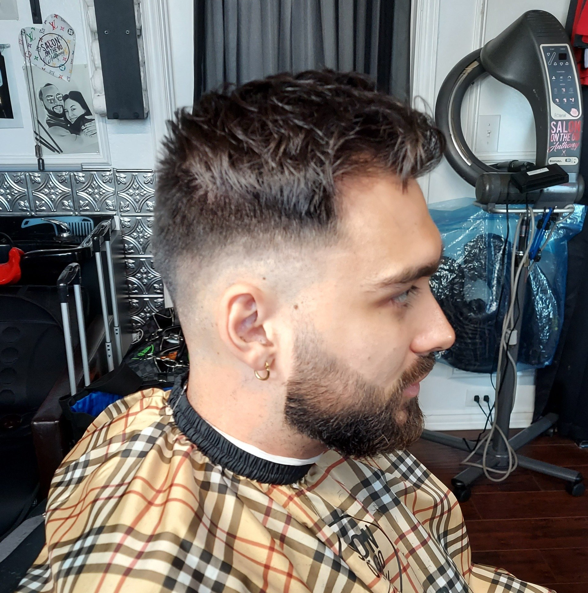 A man with a beard is getting his hair cut at a barber shop.