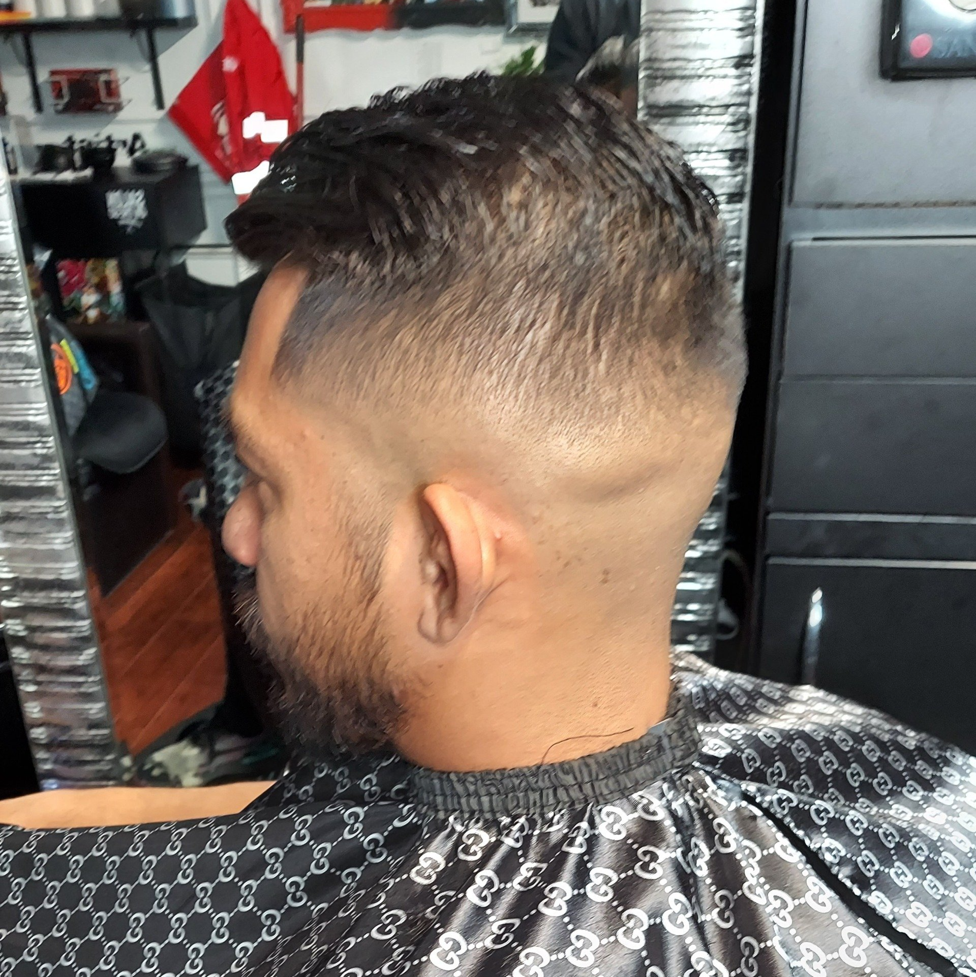 A man with a beard is getting his hair cut at a barber shop