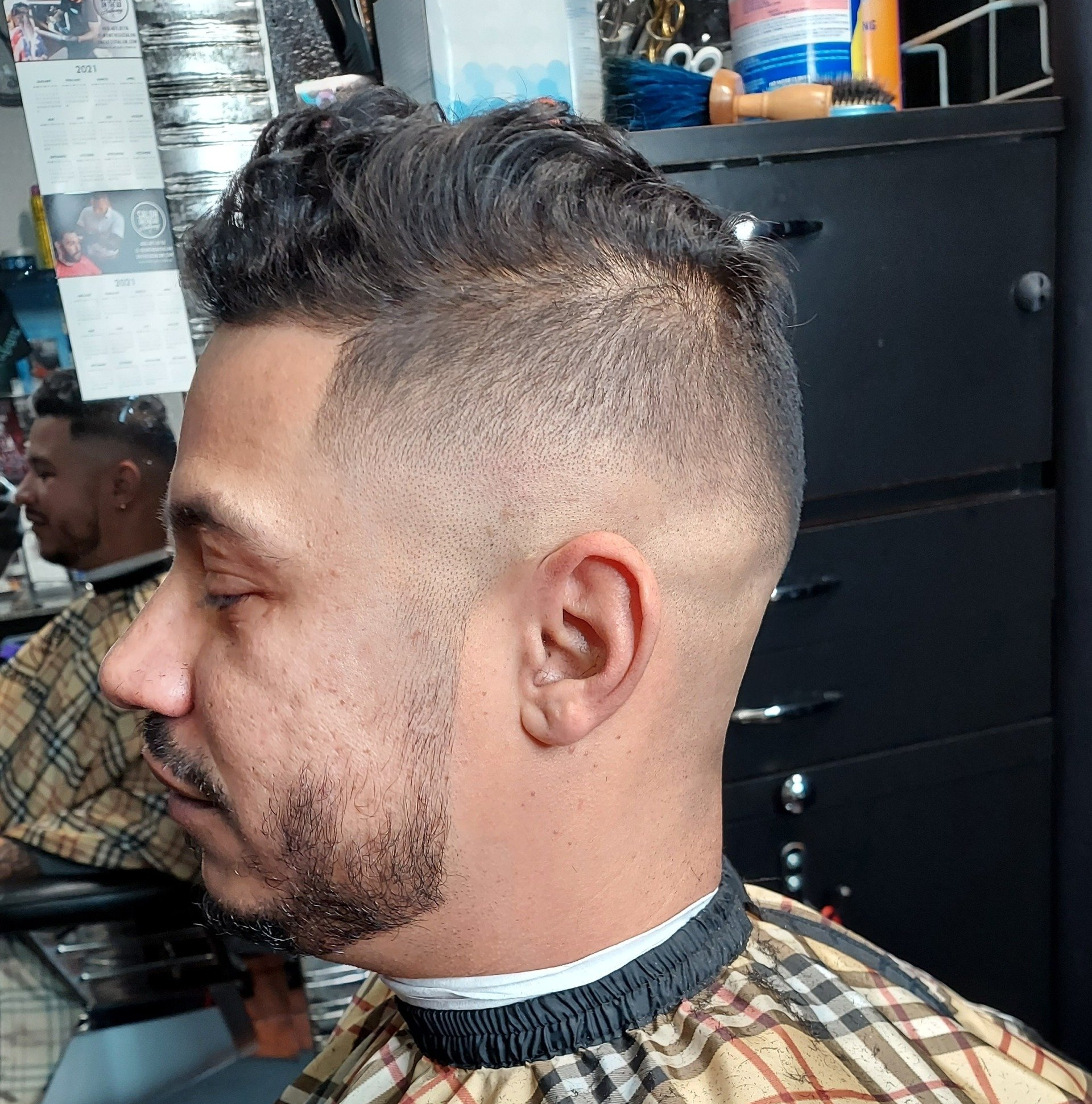 A man with a beard is getting his hair cut at a barber shop.