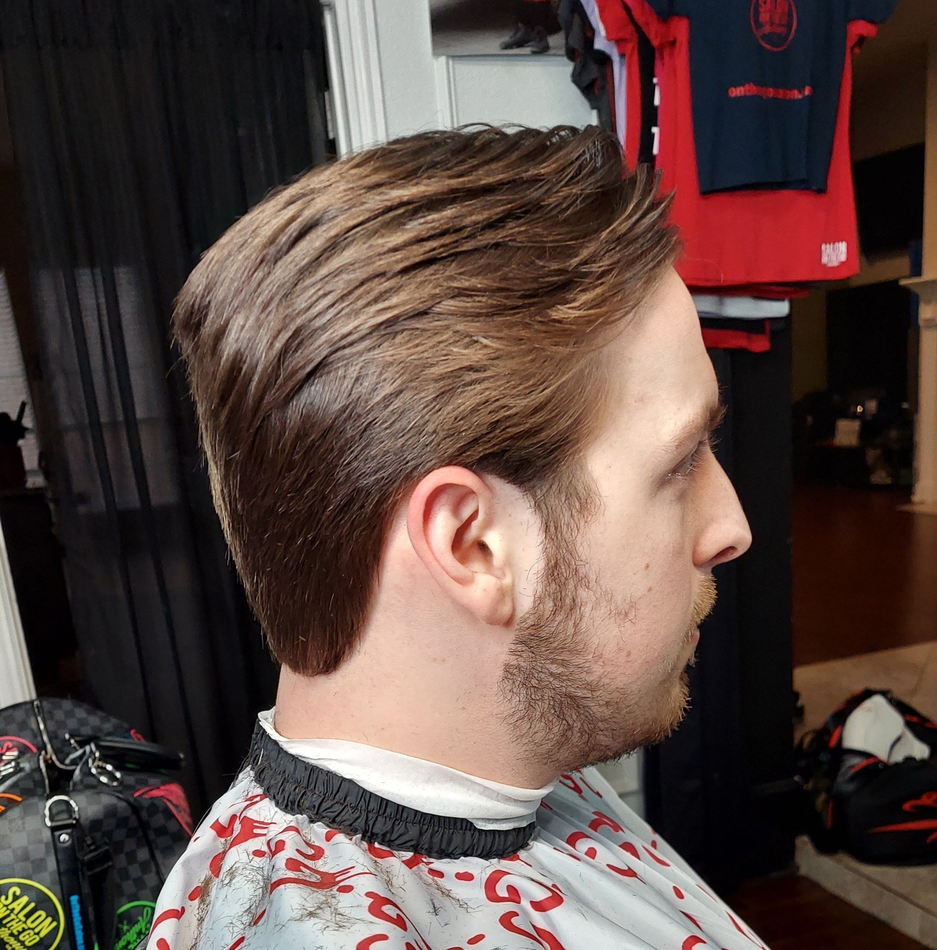 A man with a beard is getting his hair cut by a barber