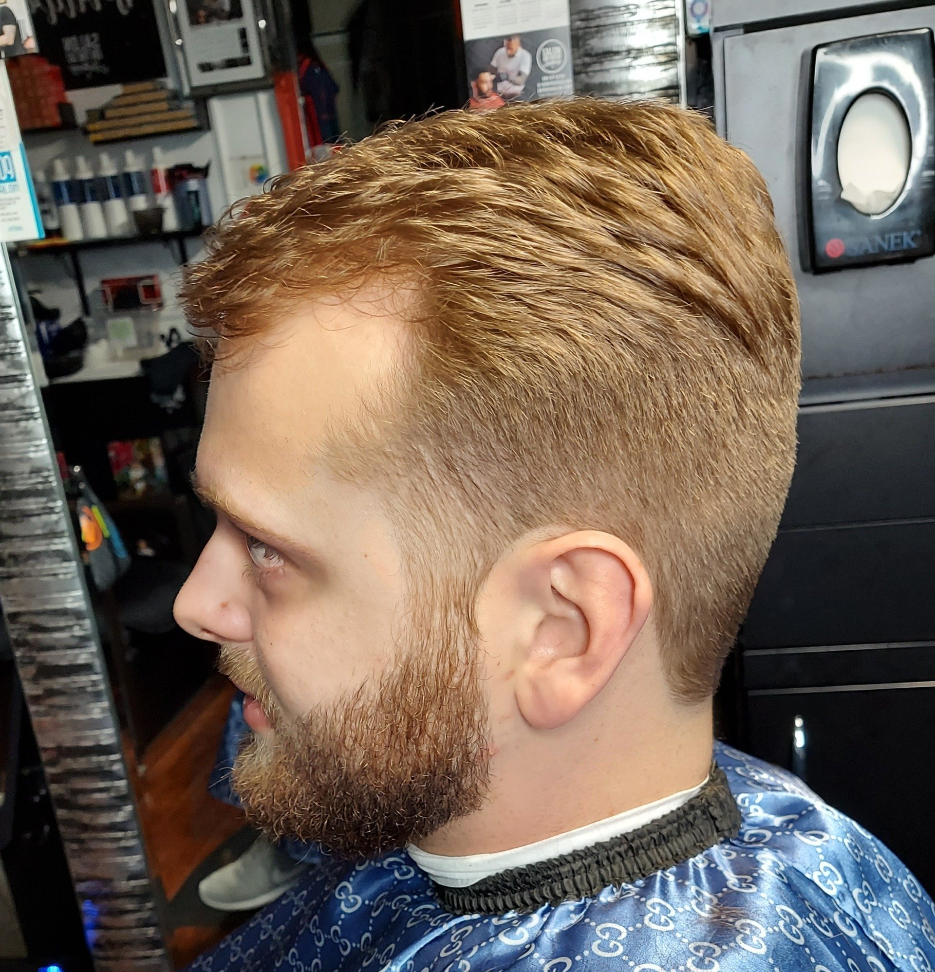 A man with a beard is getting his hair cut at a barber shop.