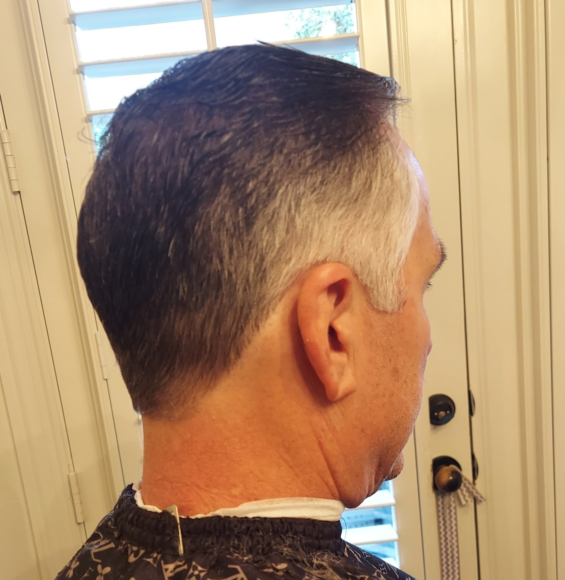 A man with gray hair is wearing a black cape