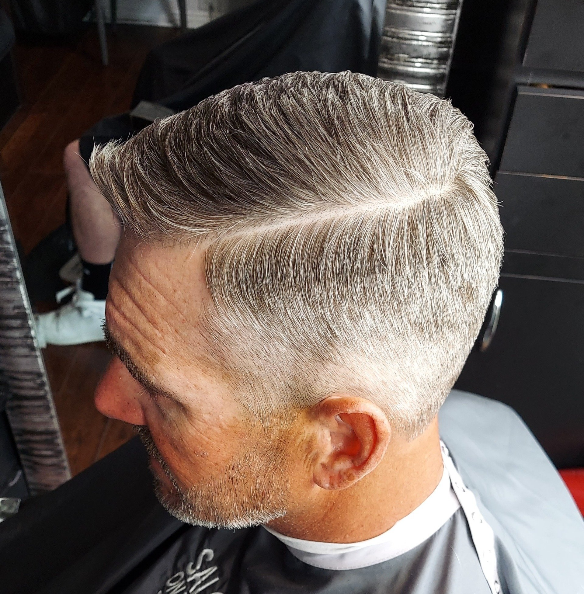 A man with a beard is getting his hair cut by a barber