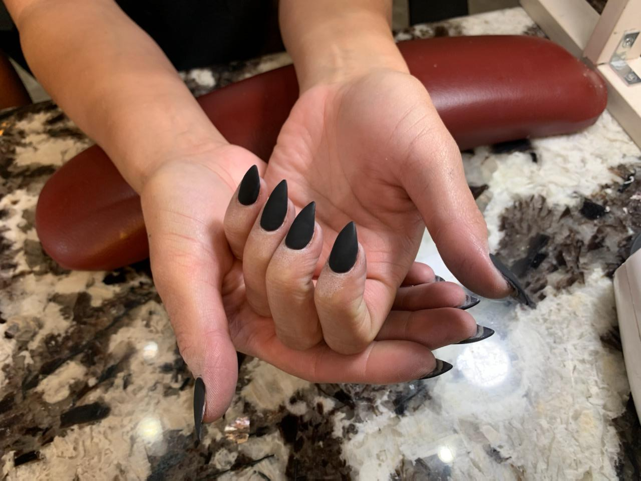 A close up of a person 's hands with black nails