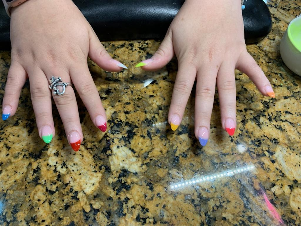 A woman 's hands with colorful nails and a ring on her finger.