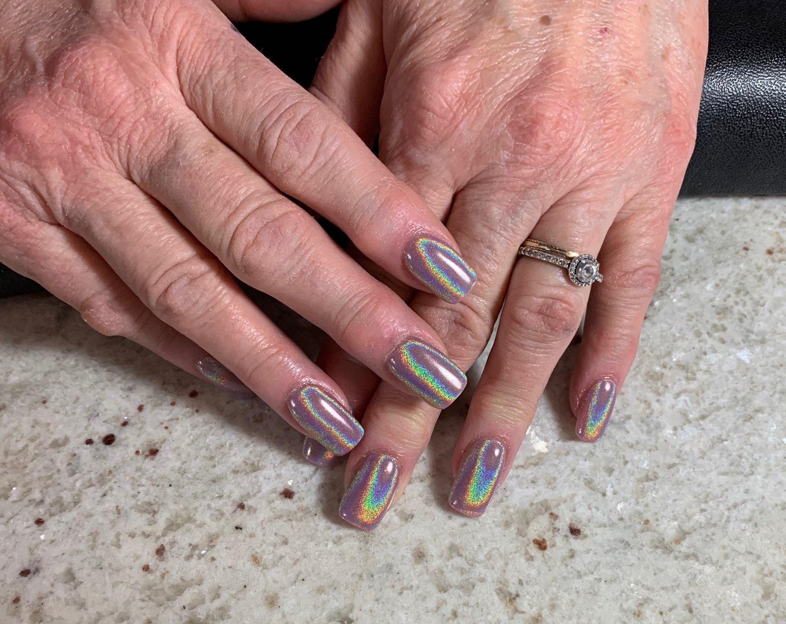 A woman 's hands with holographic nails and a ring on her finger.