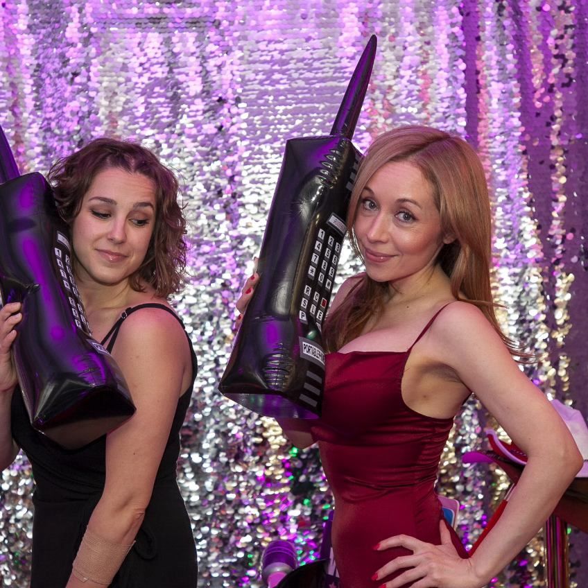 Two women standing next to each other holding inflatable phones