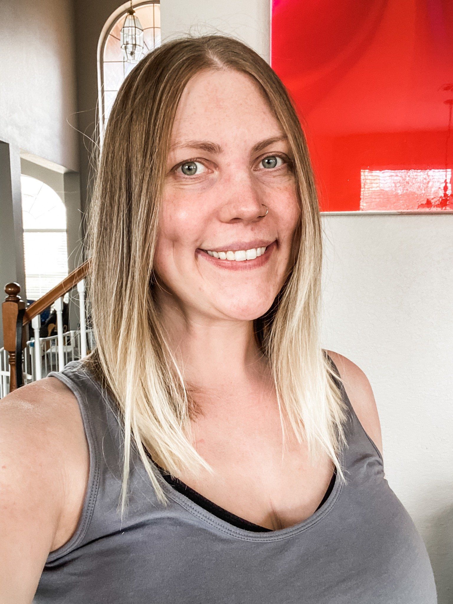 A woman in a gray tank top is smiling for the camera.
