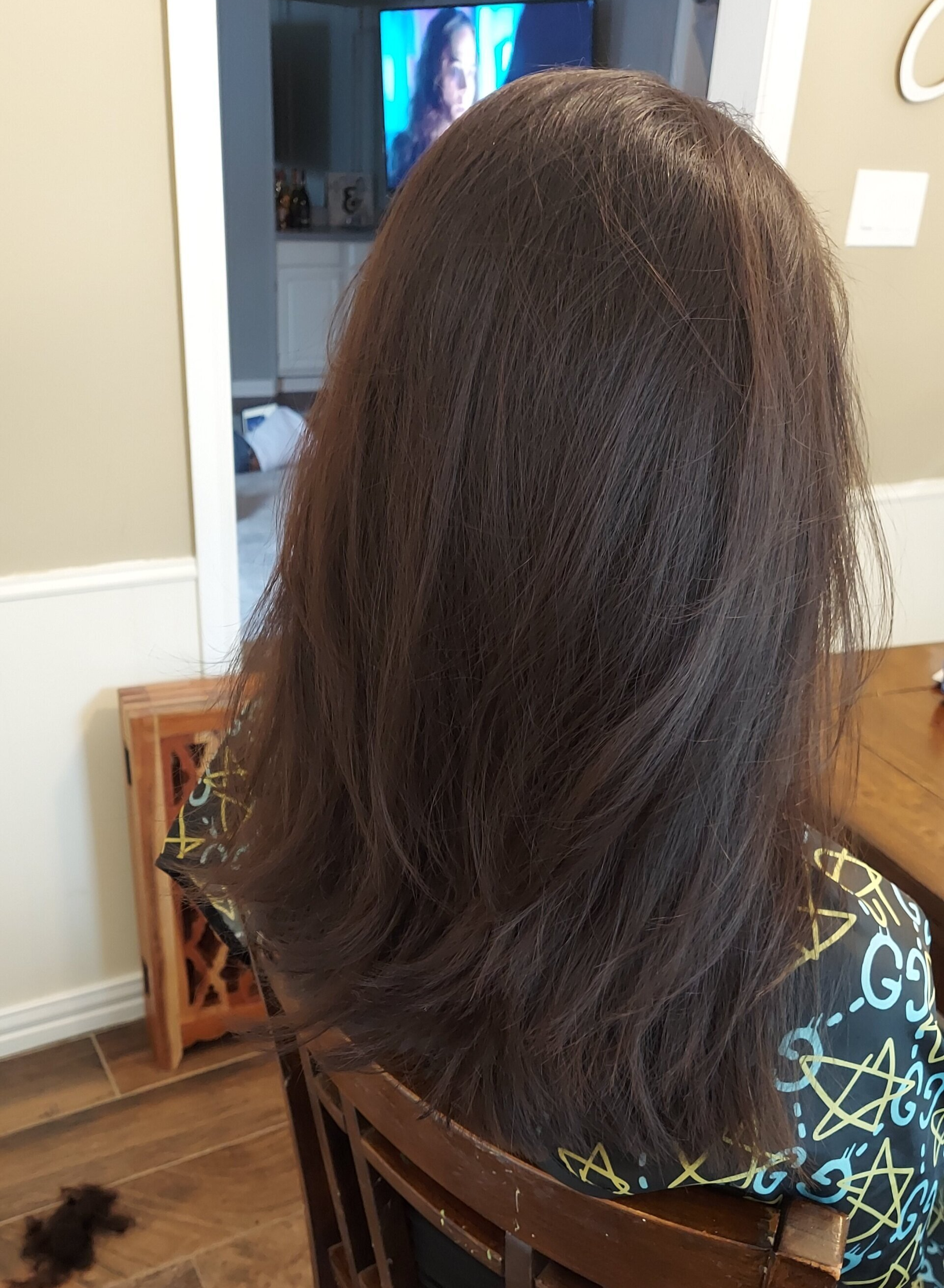 A woman with long hair is sitting in a chair in front of a television.