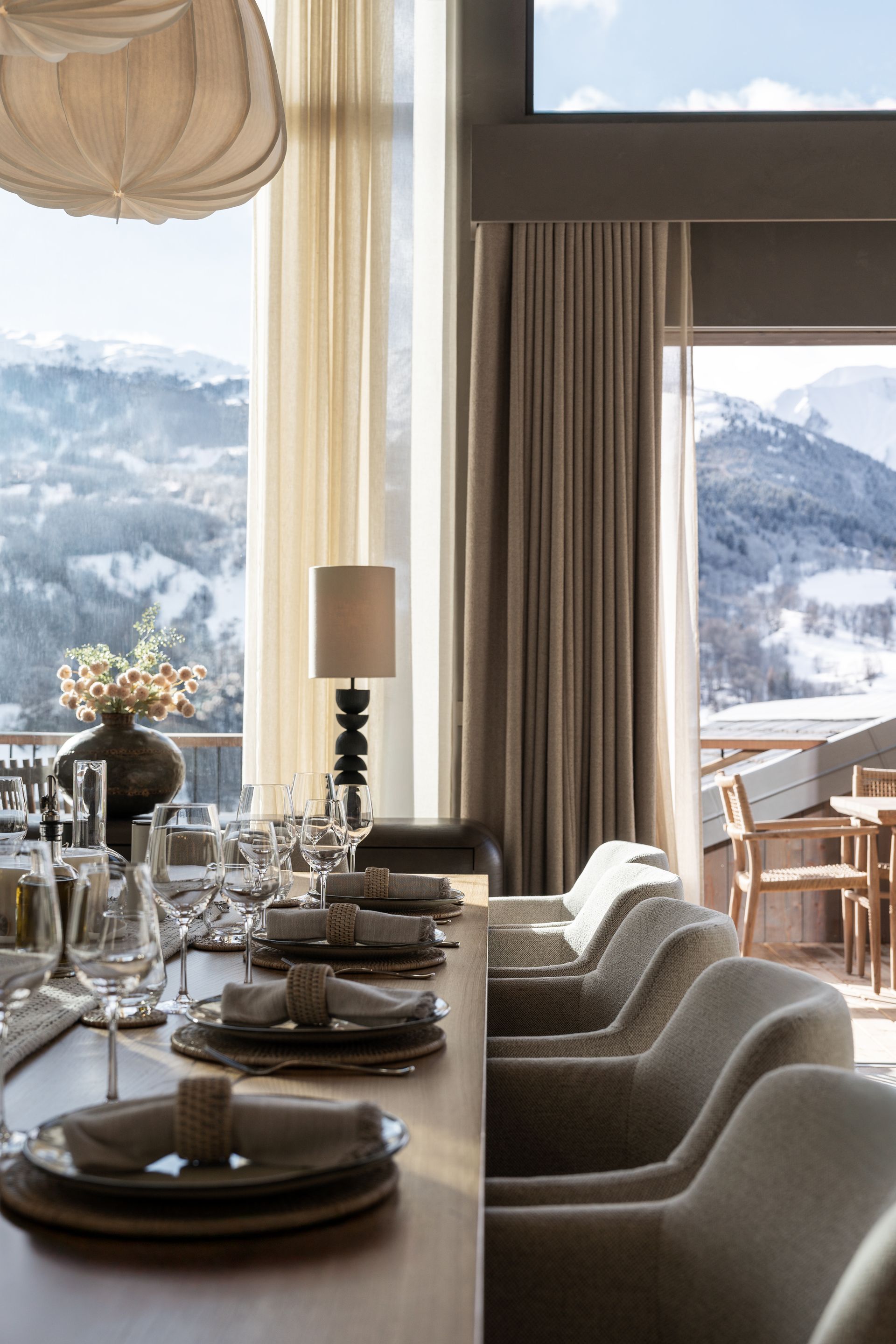Chalet Escapade A dining room table with plates , glasses , and chairs and a view of the mountains.