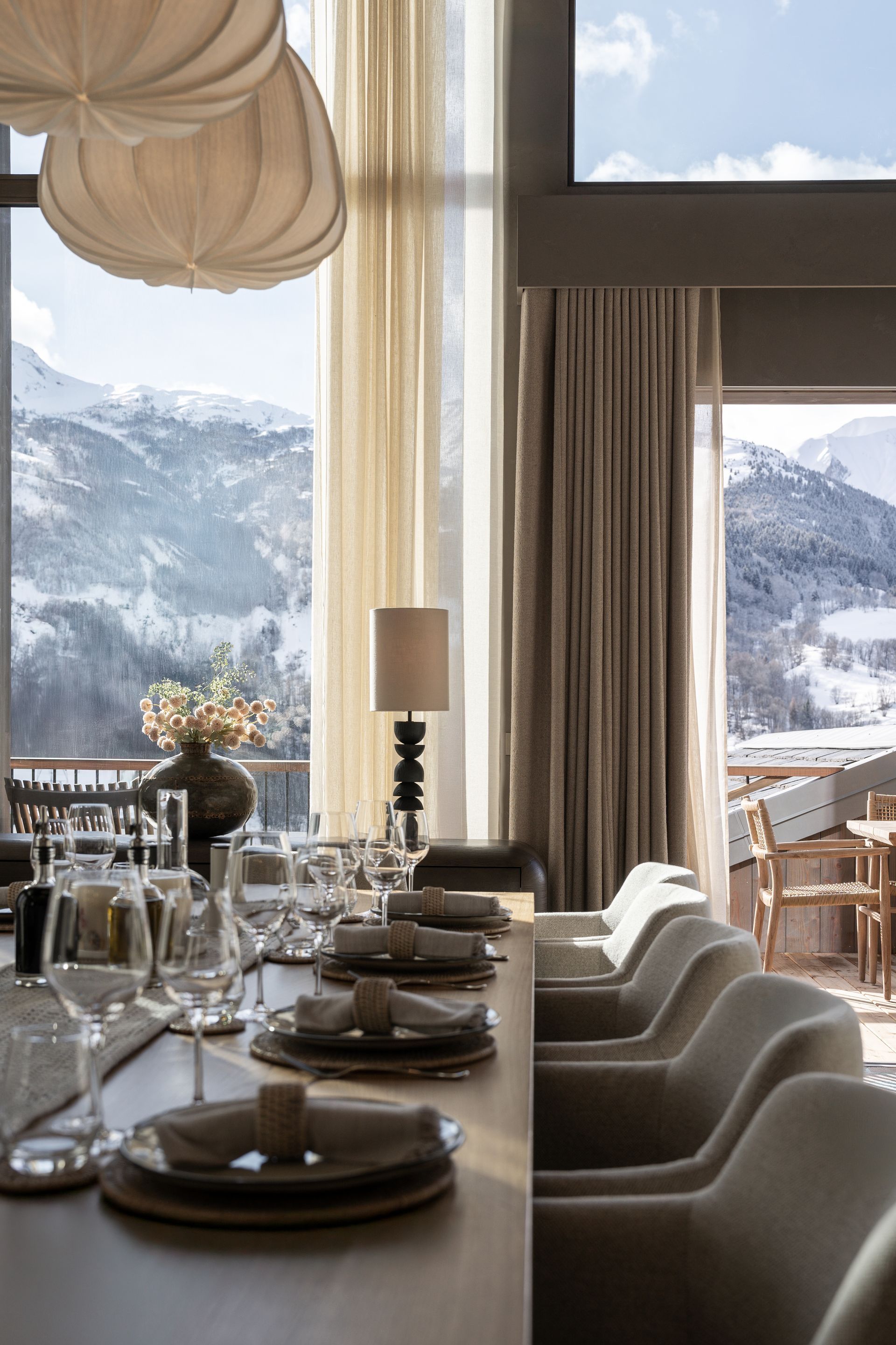 Chalet Escapade A dining room with a long table and chairs and a view of the mountains.