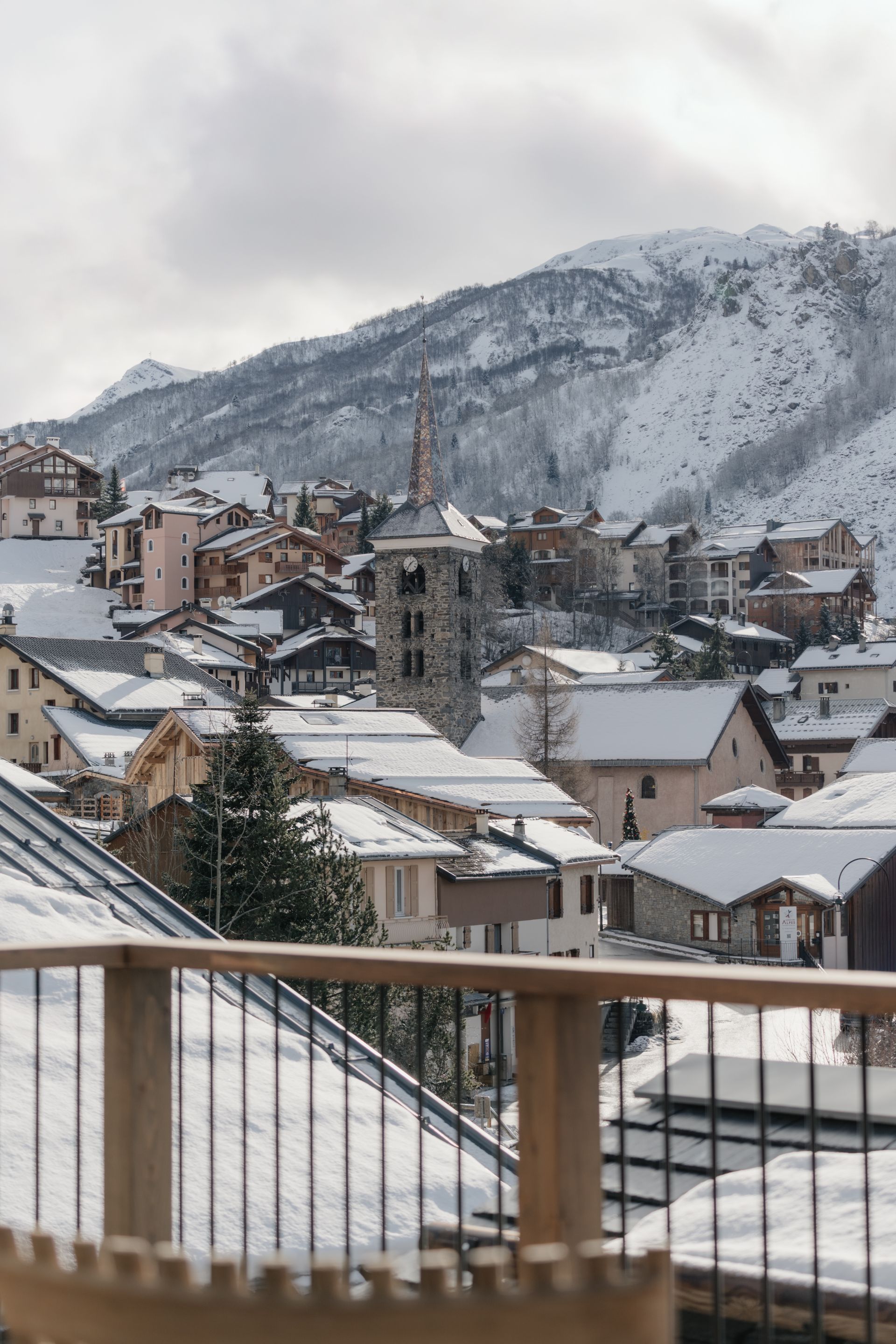 Chalet Escapade A view of a snowy town from a balcony with mountains in the background.