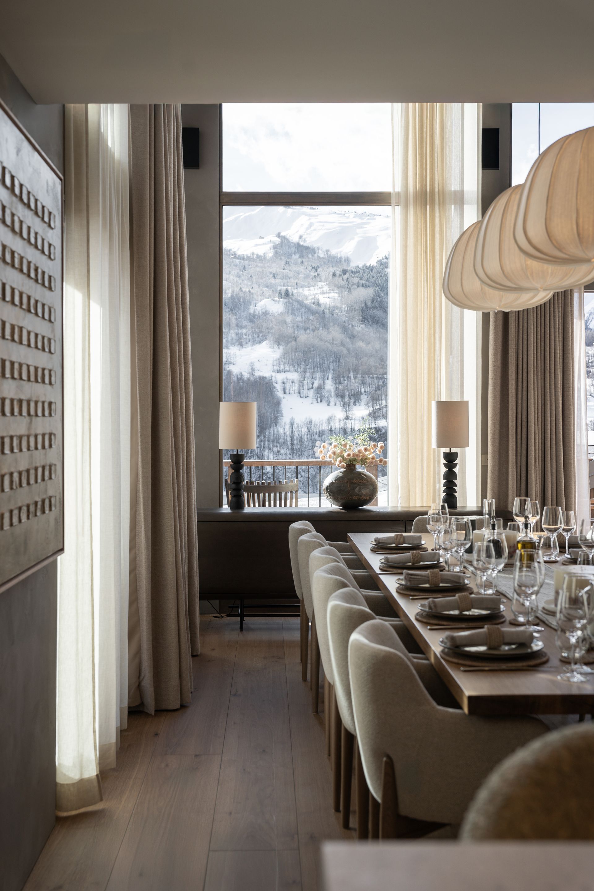 Chalet Escapade A dining room with a long table and chairs and a large window.