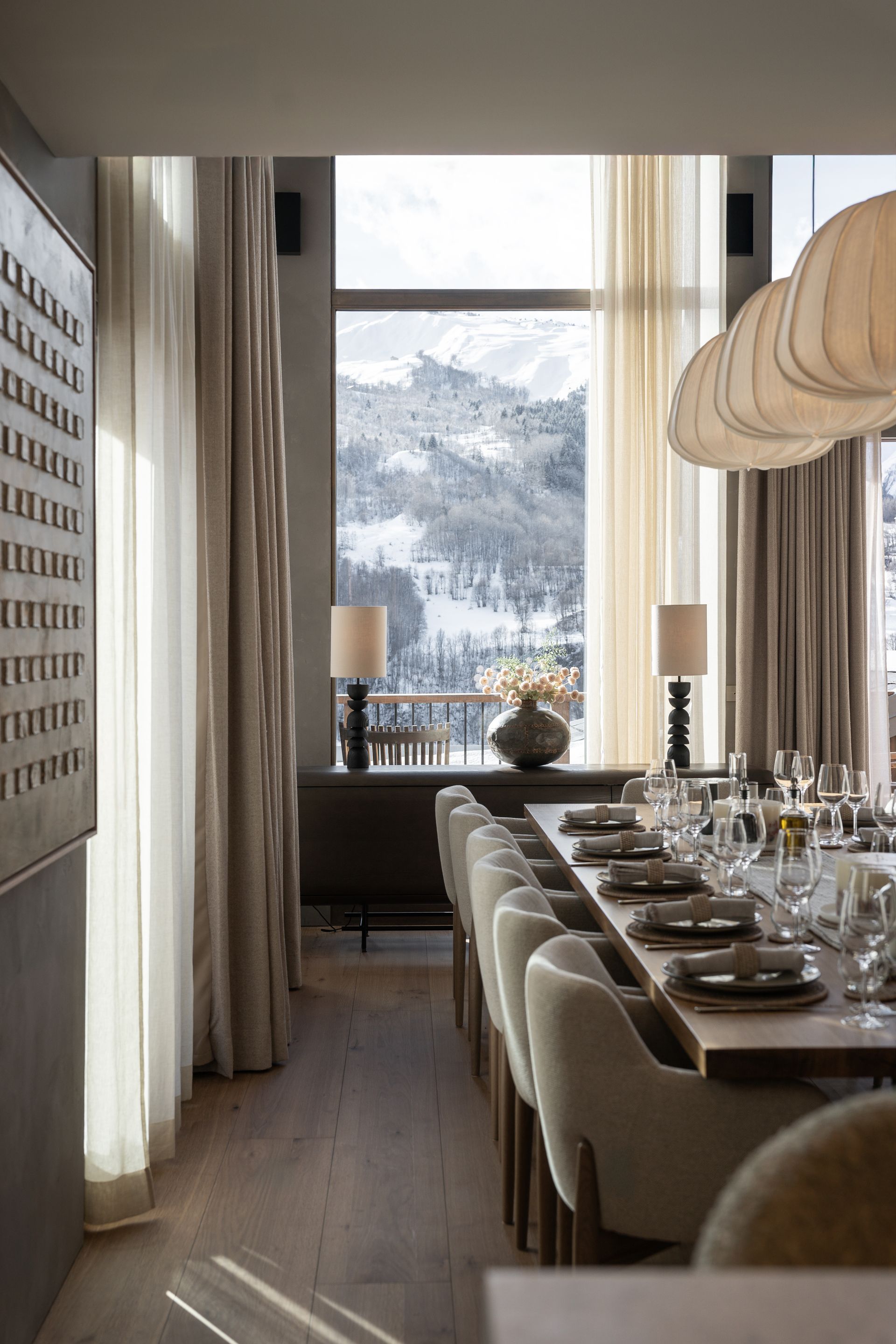 Chalet Escapade A dining room with a long table and chairs and a large window.