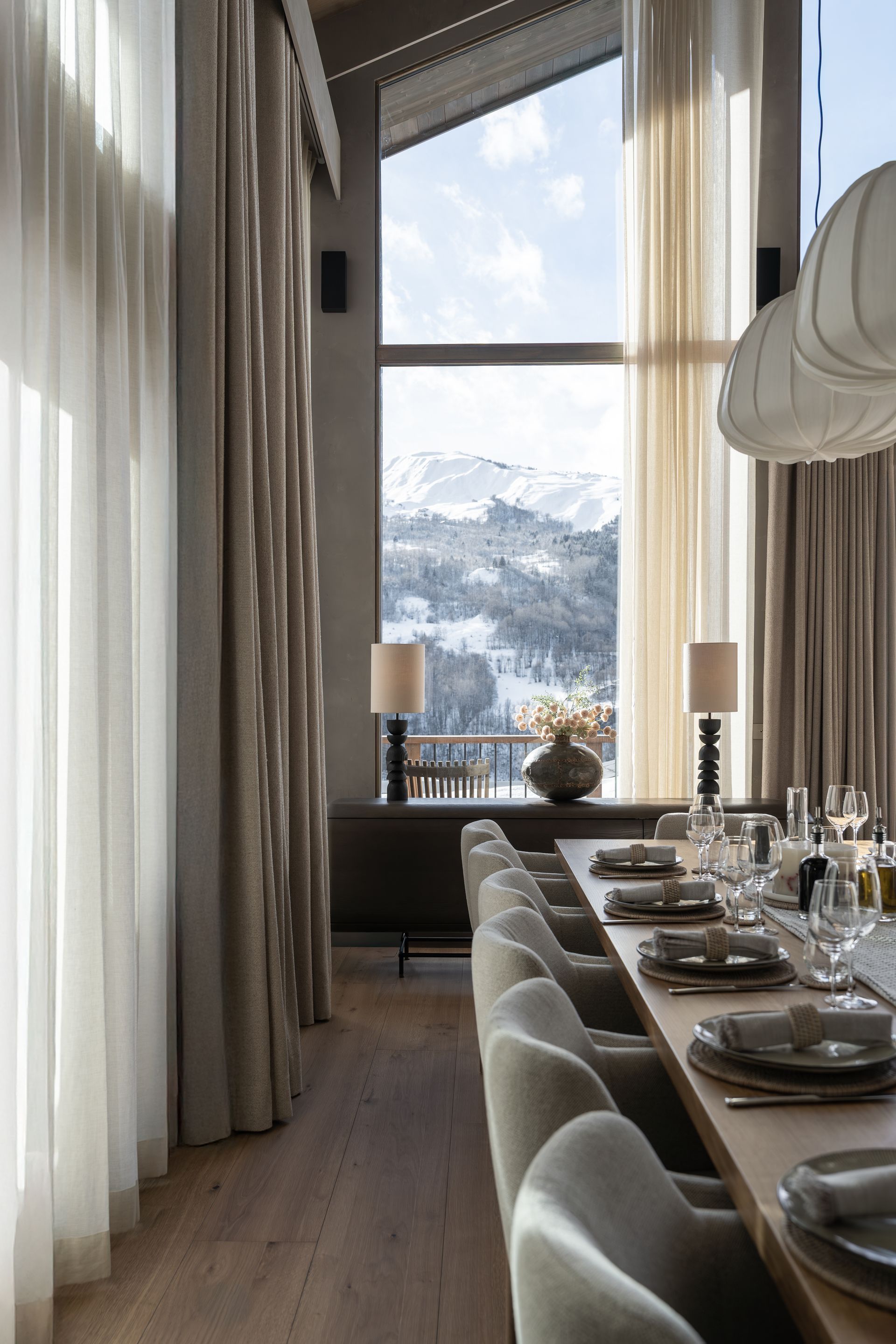 Chalet Escapade A dining room with a long table and chairs and a large window.