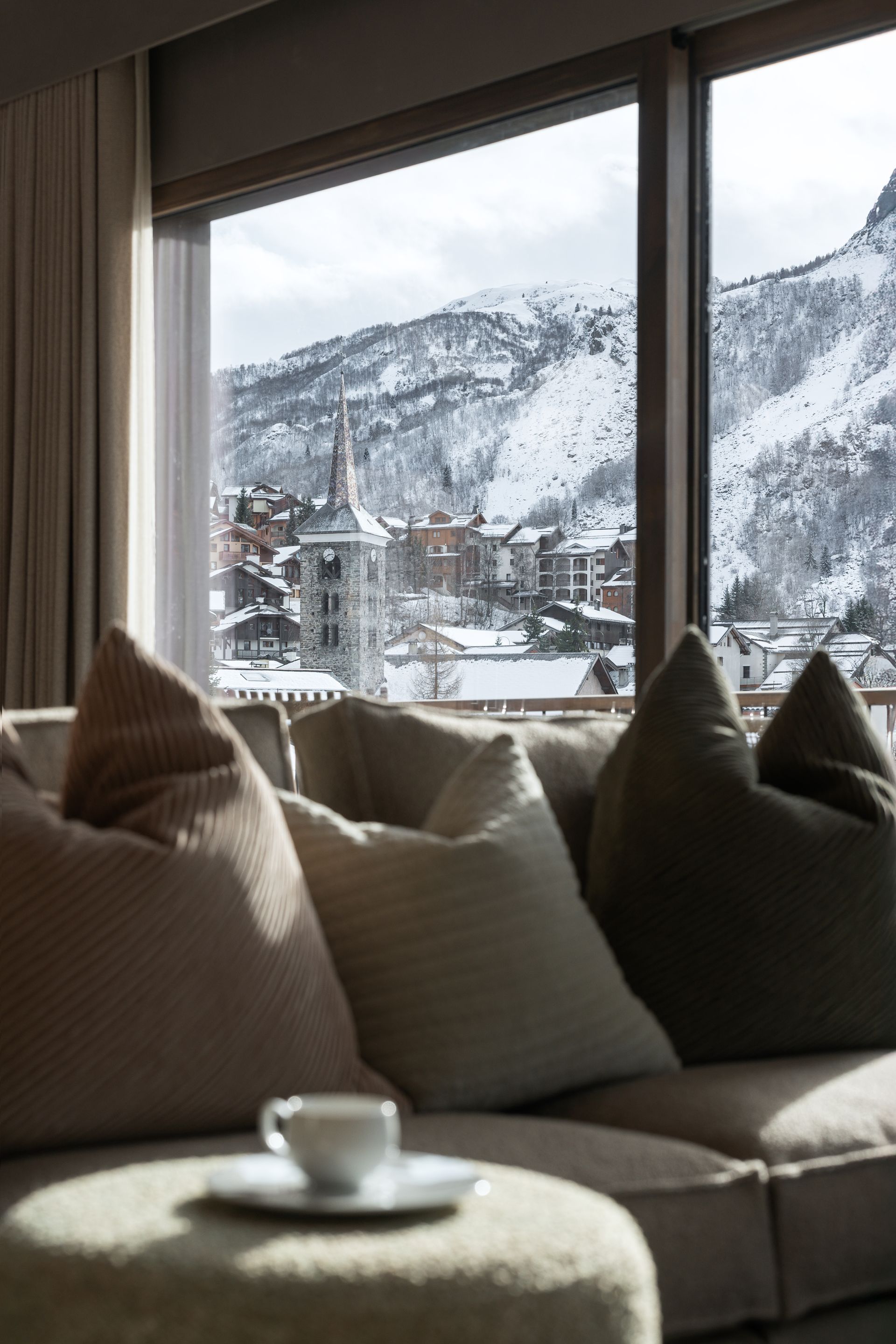 Chalet Escapade A living room with a couch and a large window with a view of a snowy mountain.