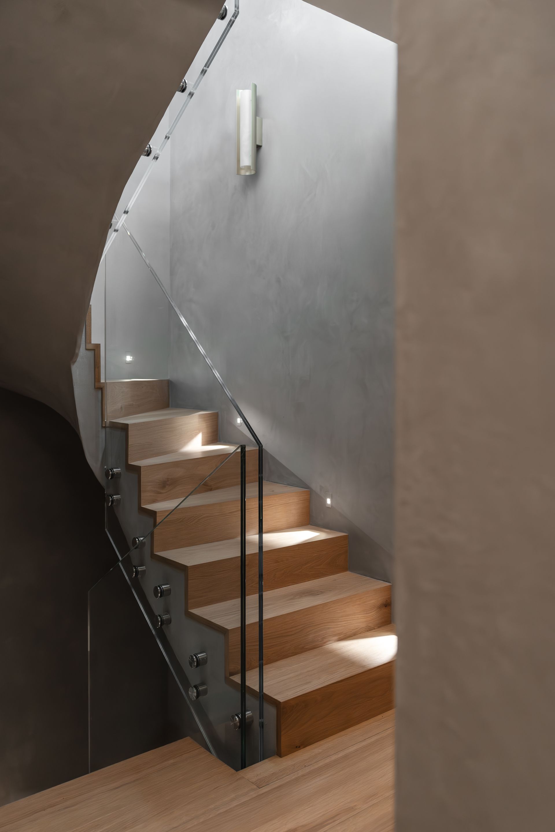 Chalet Escapade A spiral staircase with wooden steps and a glass railing.