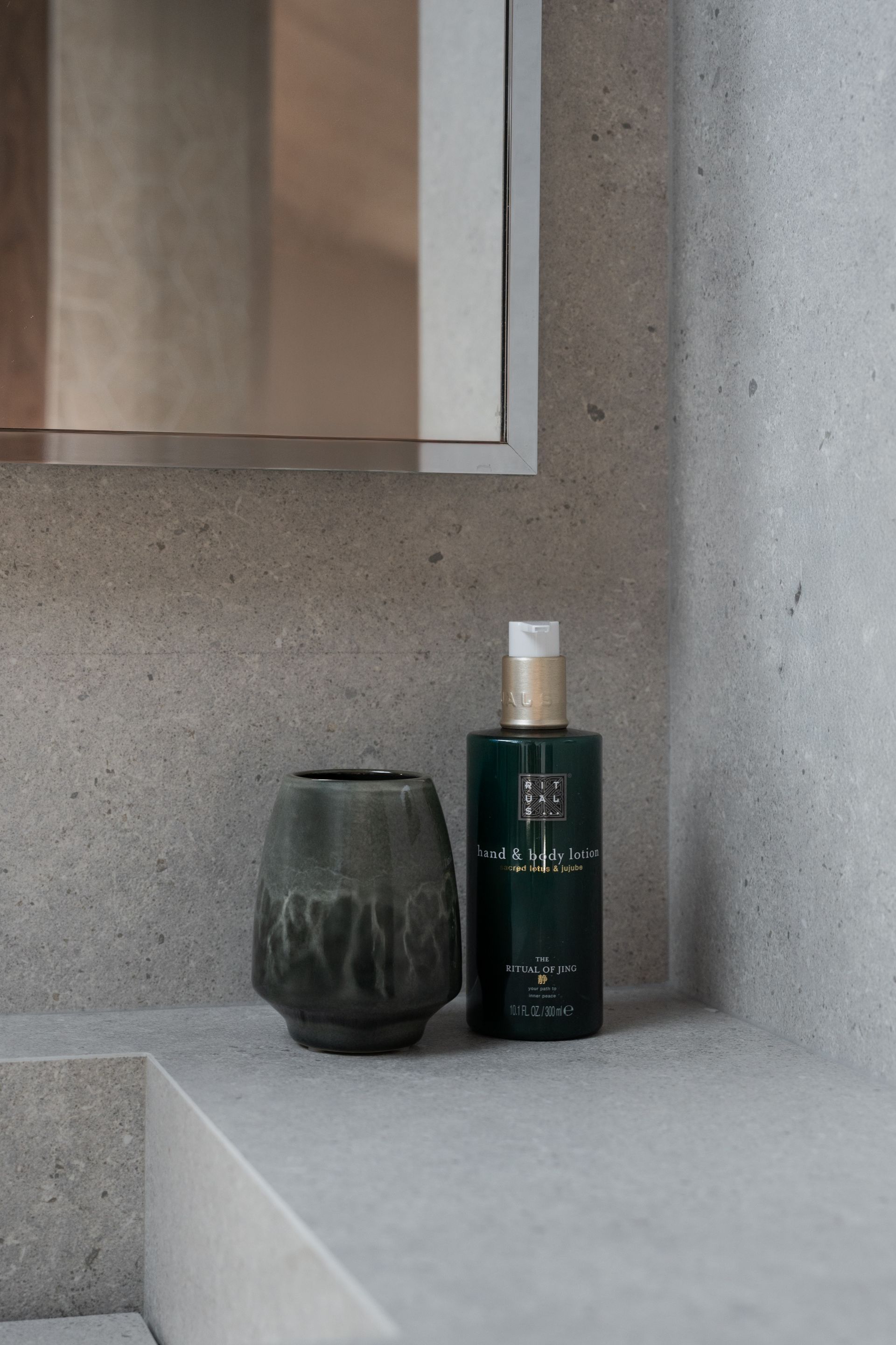 Chalet Escapade A bottle of lotion is sitting on a bathroom counter next to a vase.